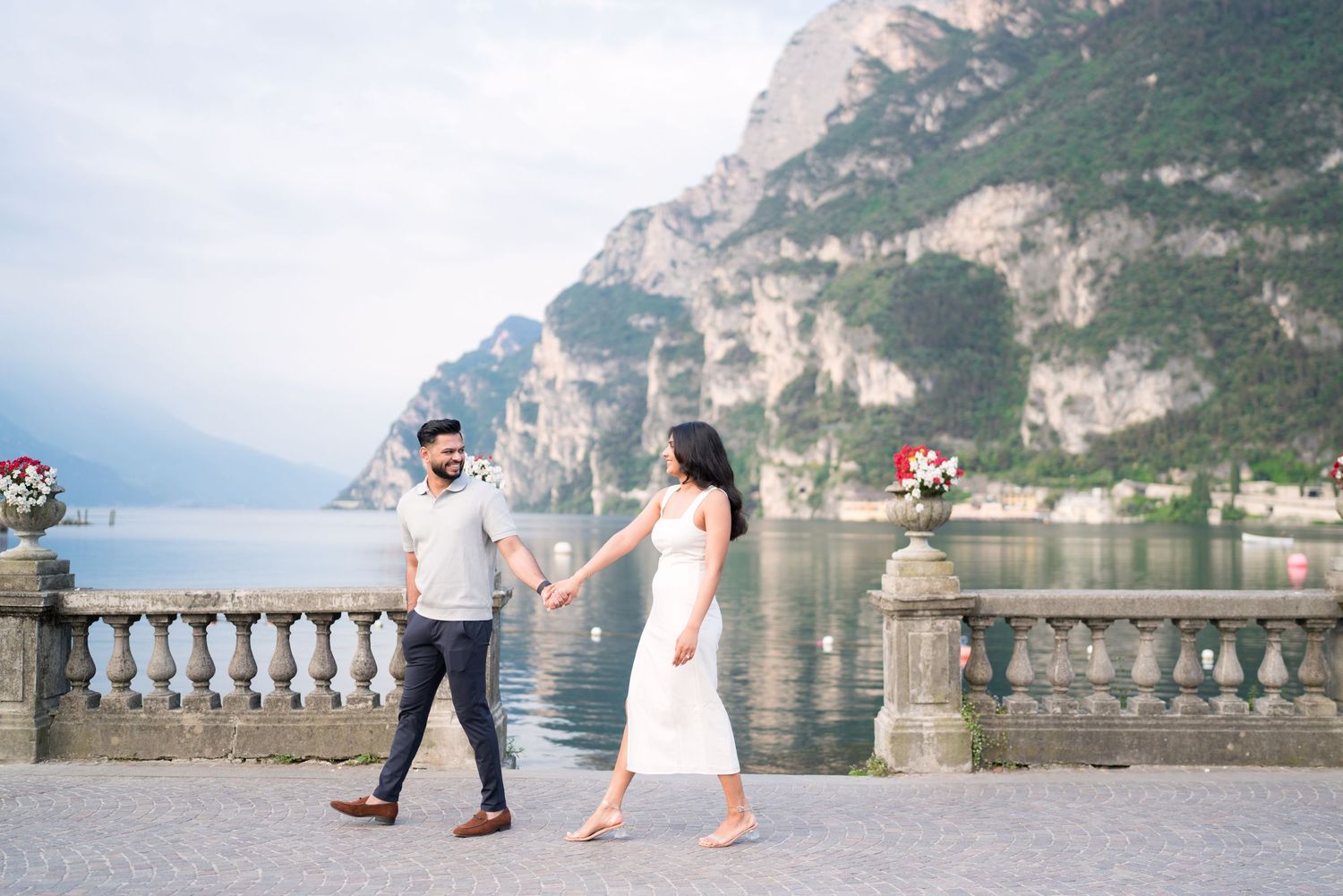 A romantic couple shares intimate moments along a scenic lakeside balustrade in Italy.