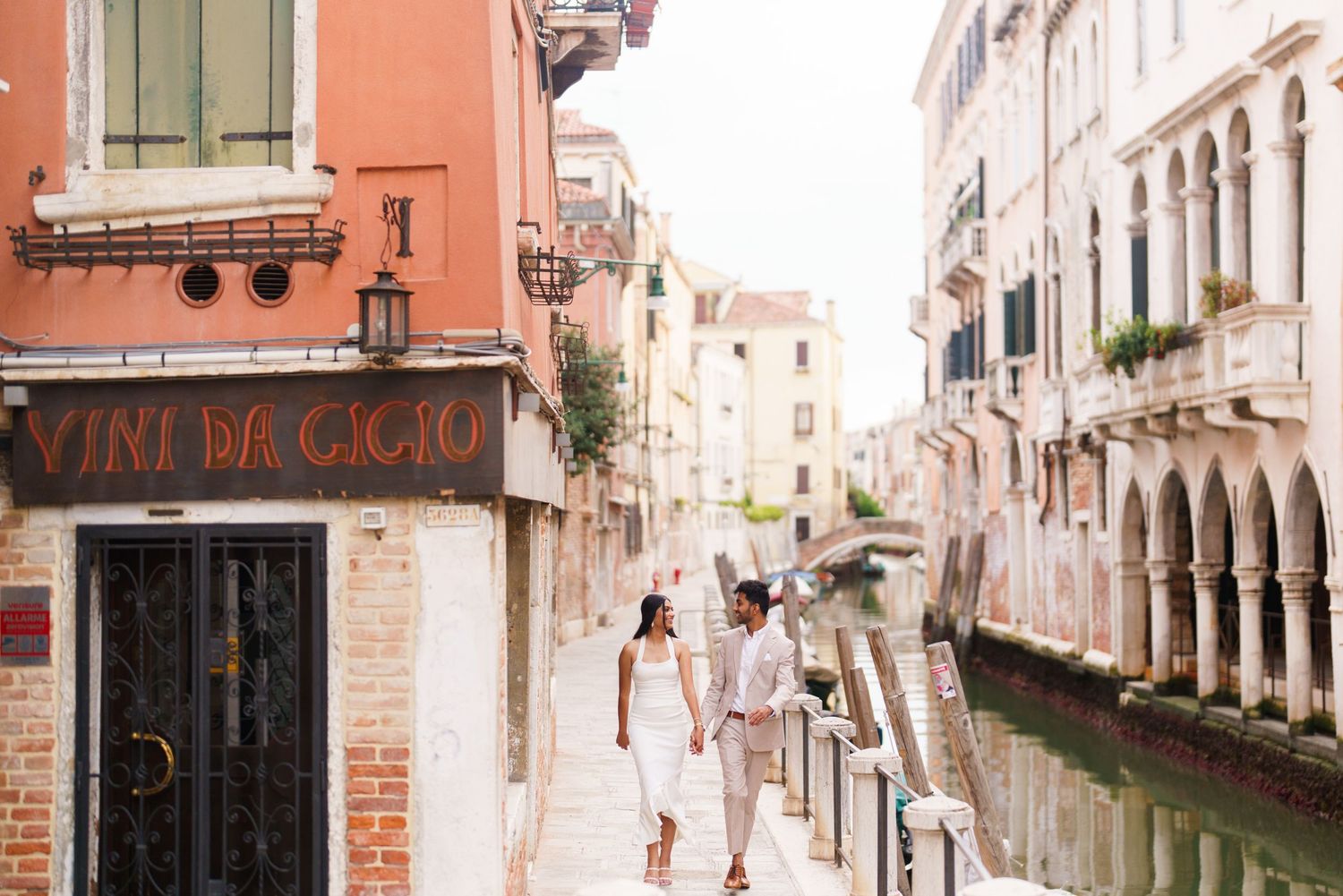 Pink and peach colored buildings line narrow canals in Venice, Italy with traditional architecture and bridges.
