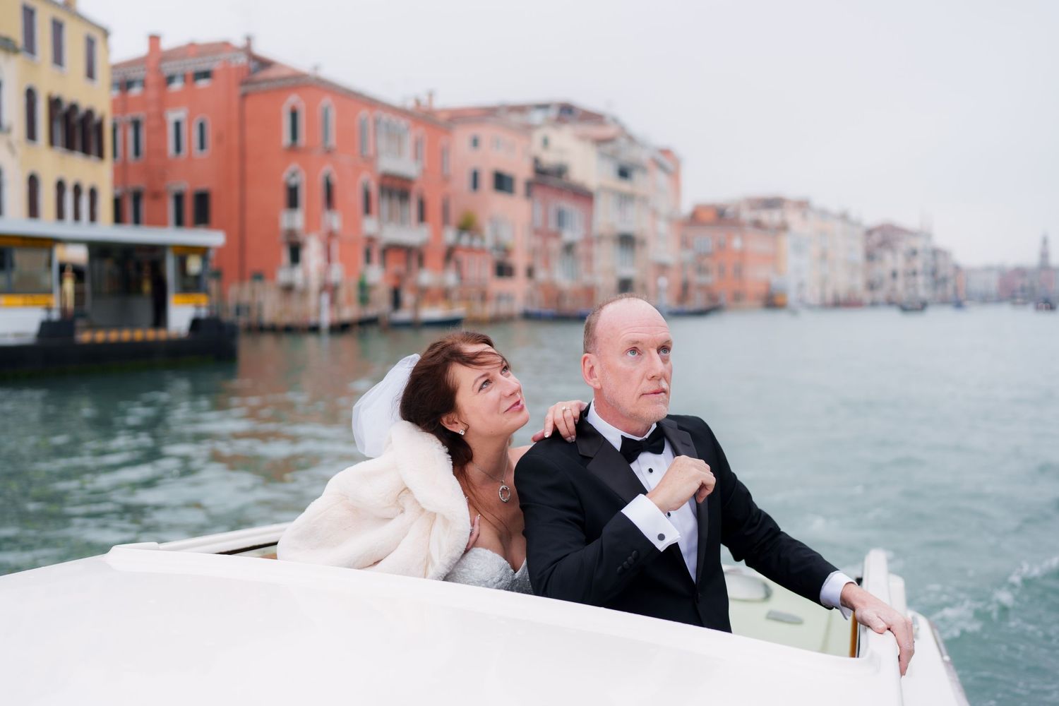 A romantic couple poses for wedding photos along the canals of Venice with historic buildings in the background.