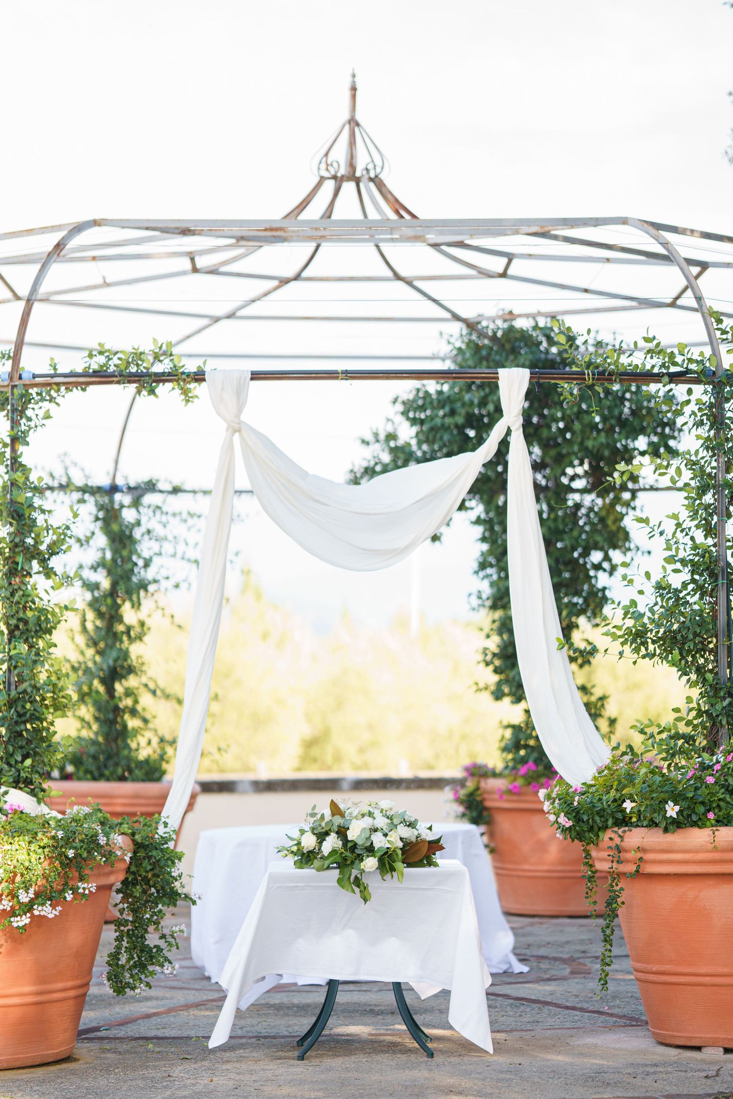 White draped gazebo with terracotta planters and garden wedding decor.