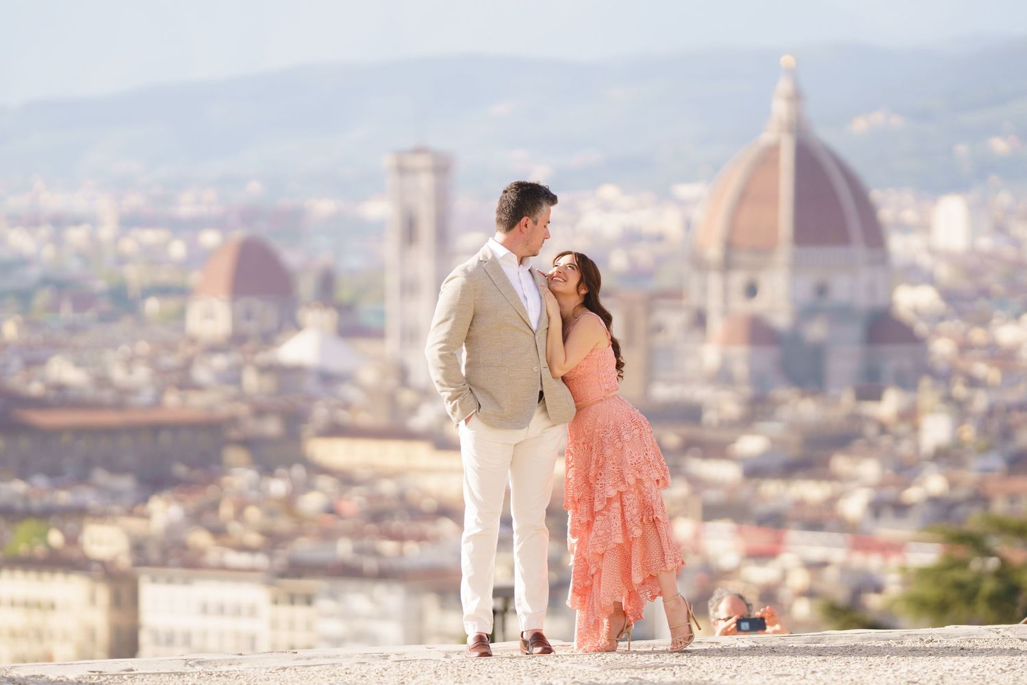 Couple in romantic poses overlooking the stunning cityscape of Florence, Italy with the iconic Duomo cathedral in view.