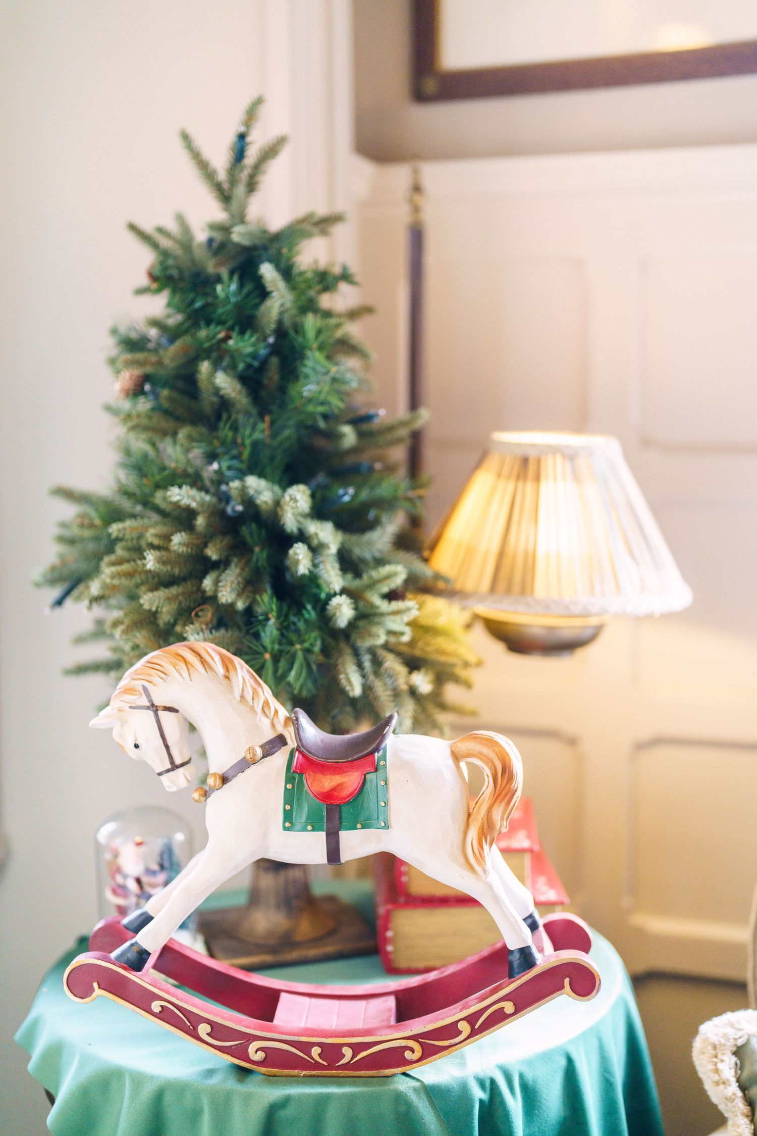 Decorative rocking horse ornaments displayed on turquoise tablecloths with evergreen centerpieces.