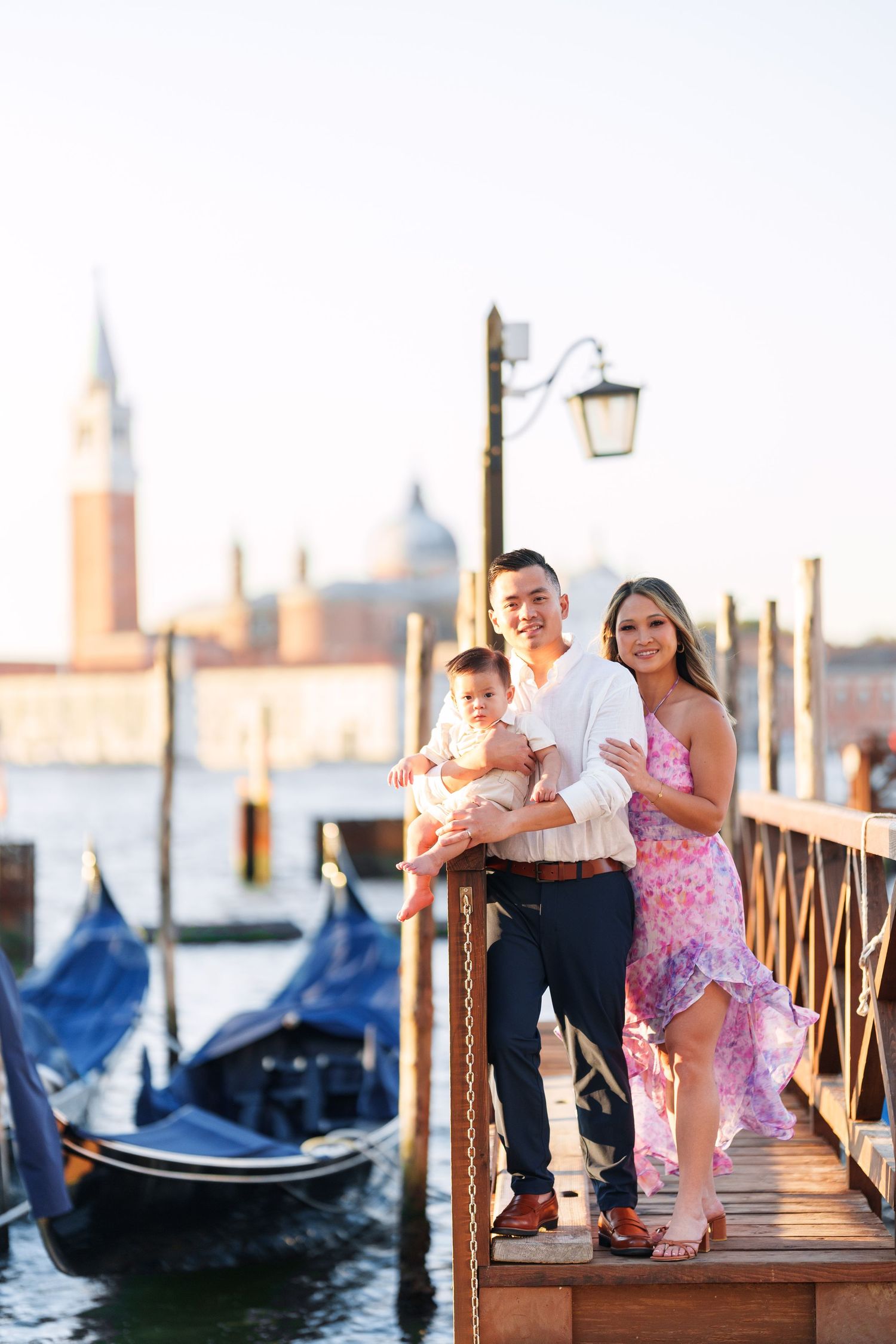 Family posing on a Venice dock with gondolas and San Giorgio Maggiore church in the golden hour background.