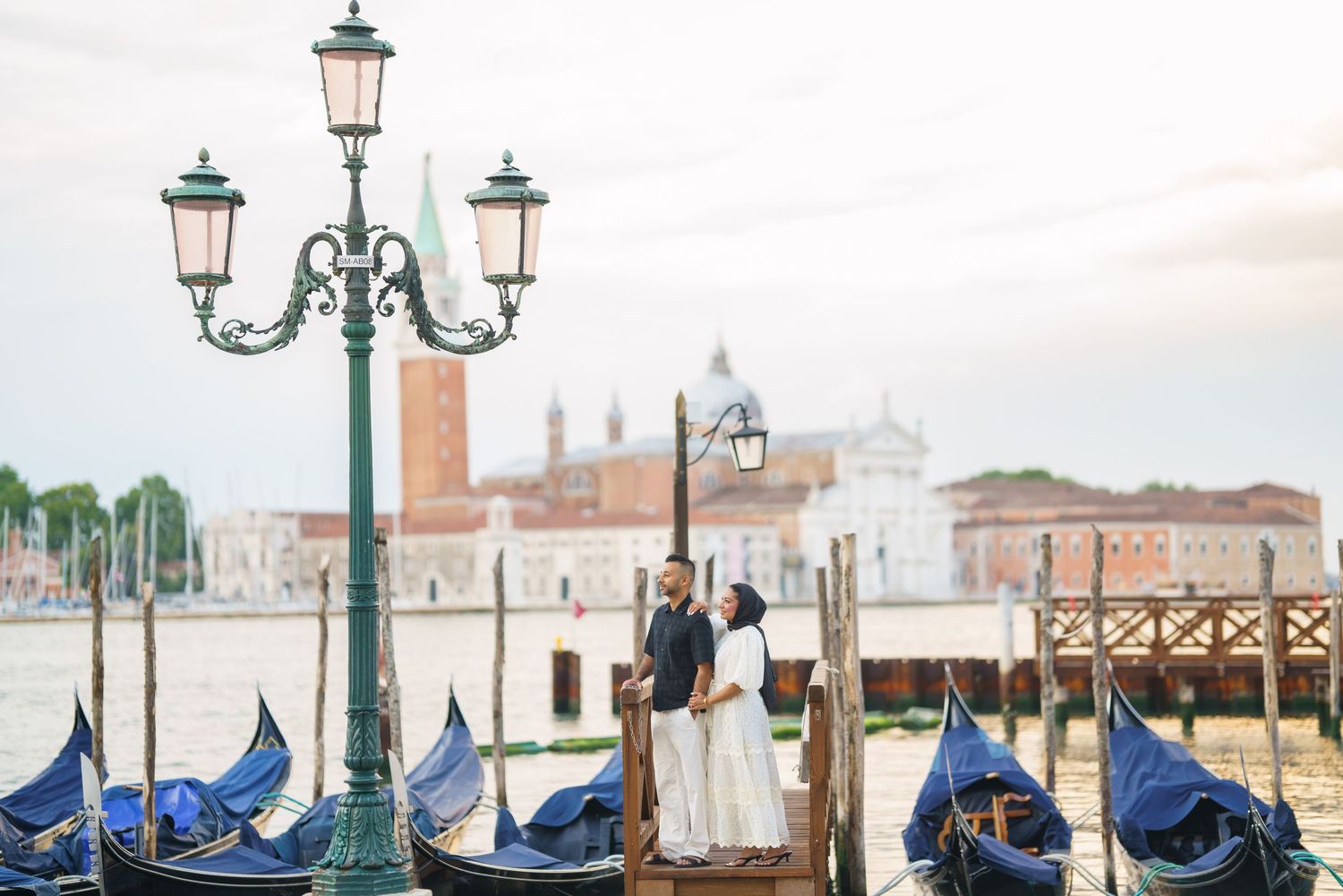 Couple embracing by gondolas on Venice Grand Canal with San Giorgio Maggiore church in background.