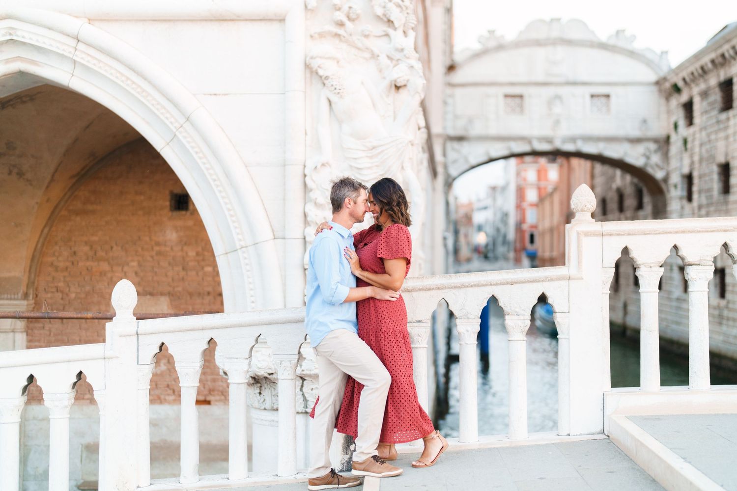 Couple sharing a romantic moment on a bridge in Venice, Italy, with the Bridge of Sighs in the background.
