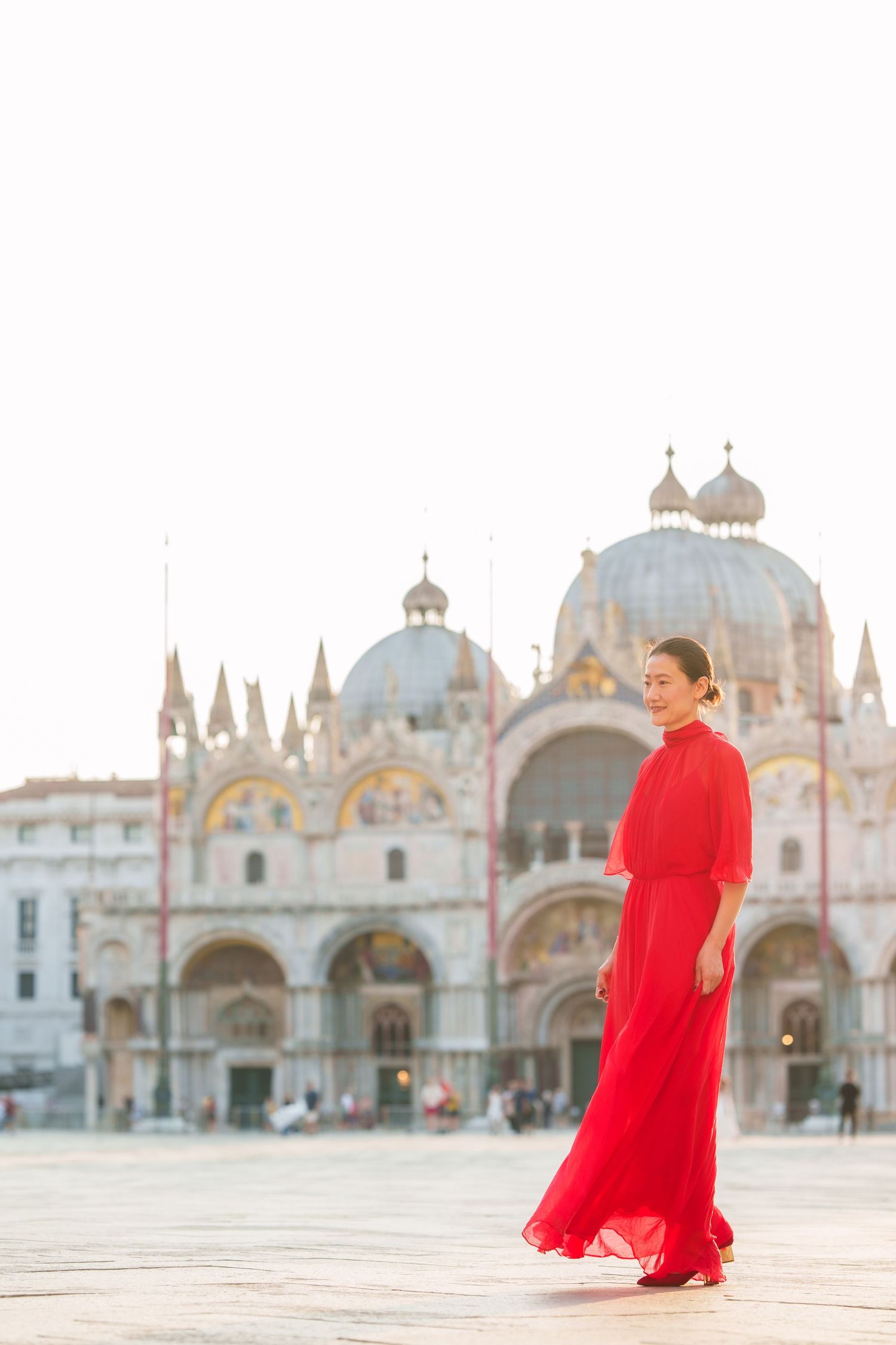 Woman in red gown at St. Mark's Square, Venice, with Basilica di San Marco in the background.