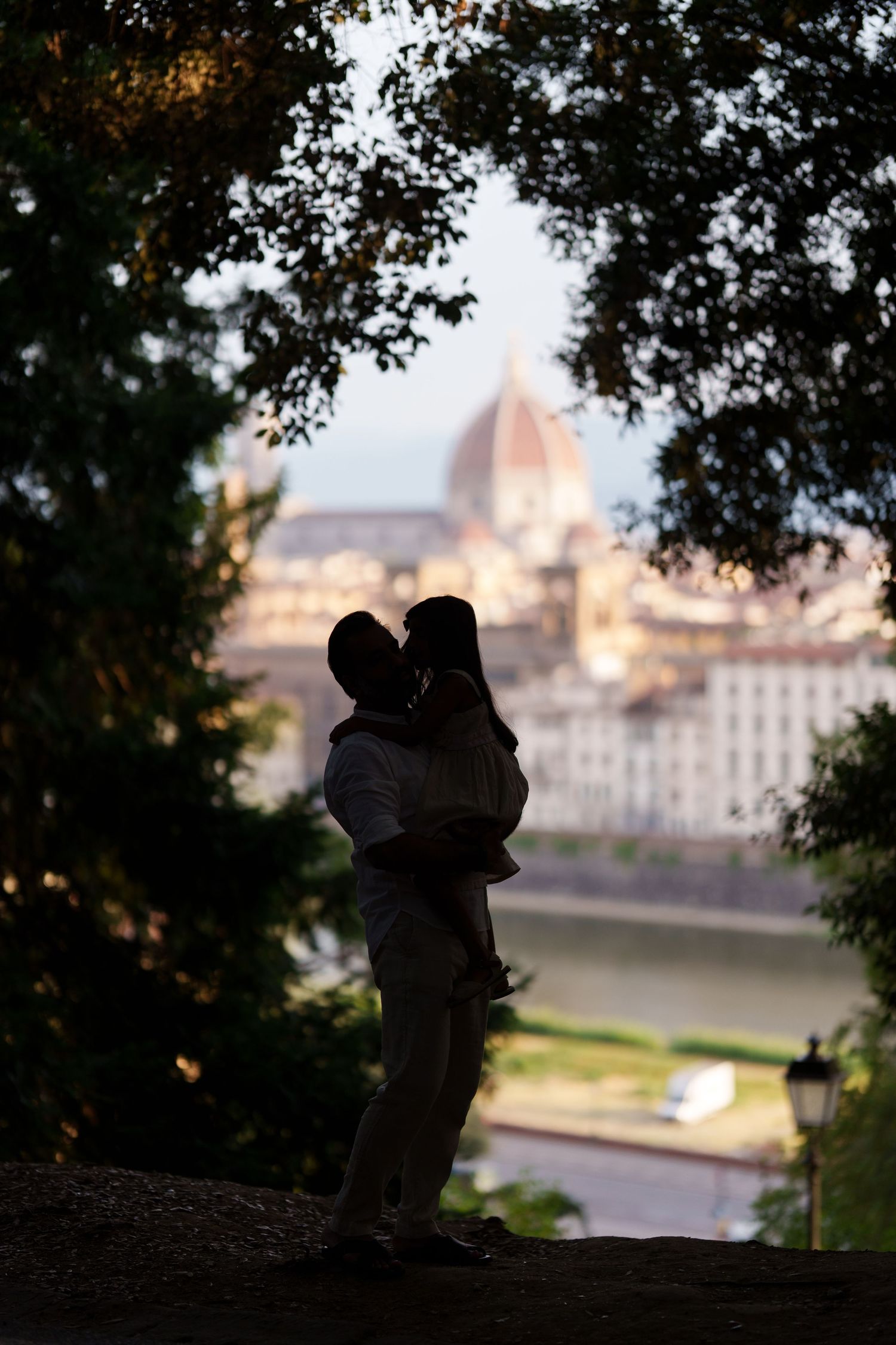 Romantic couple silhouette kissing at dusk with Florence Cathedral dome in background, Italy.
