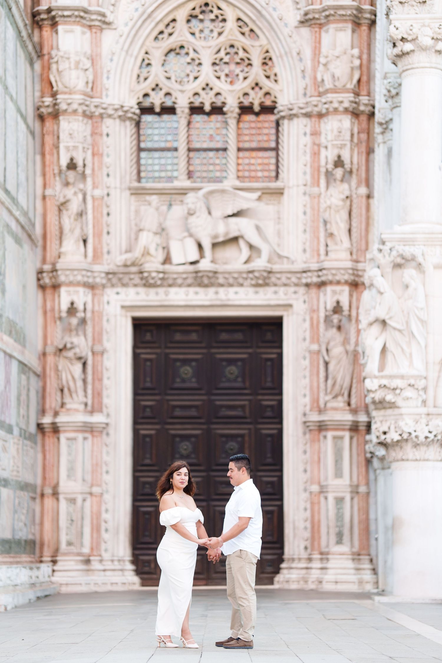 A romantic proposal moment unfolds in front of an ornate cathedral with Gothic architecture and stone carvings.
