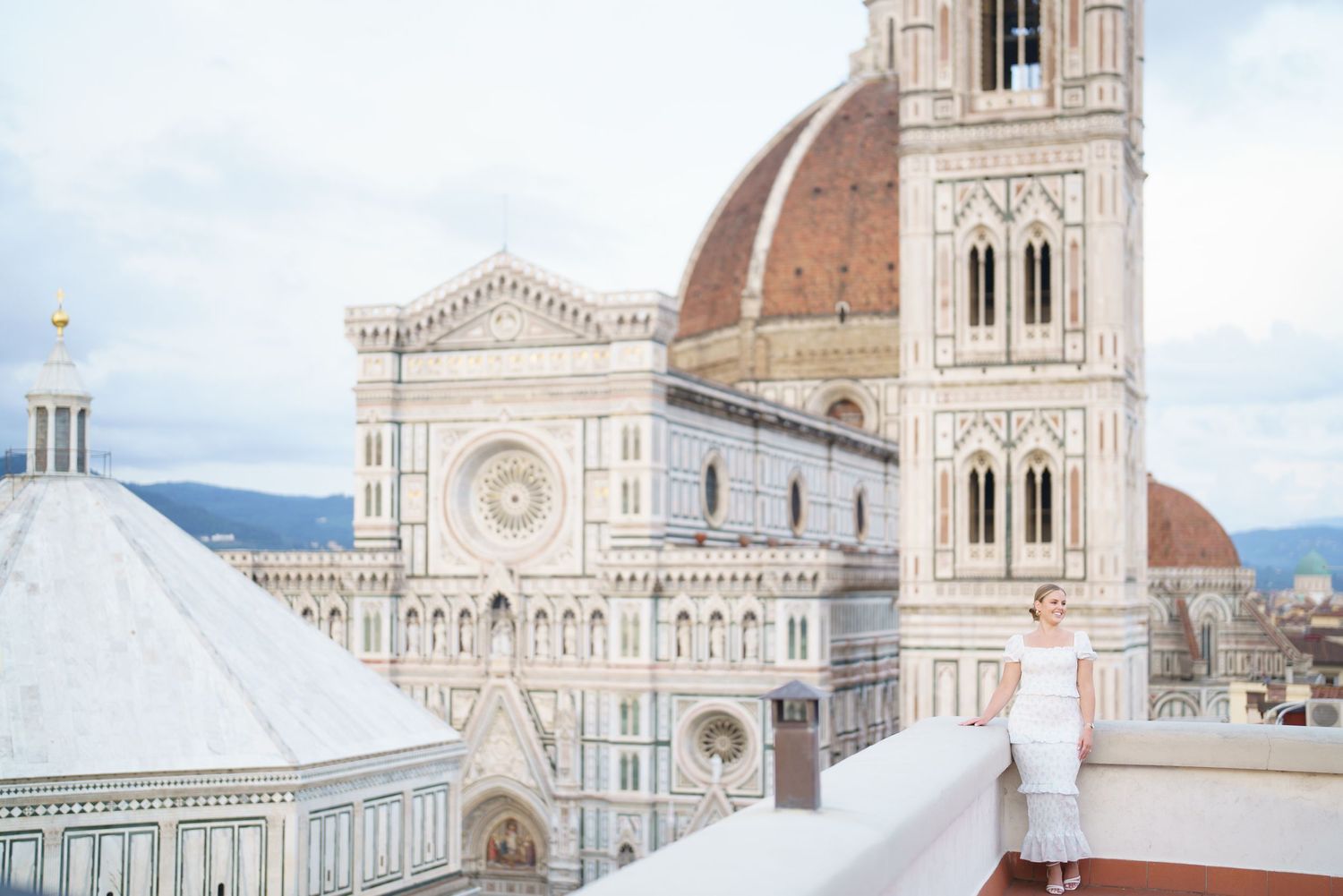 Architectural details of Florence Cathedral's iconic Duomo with its ornate marble facade and Renaissance dome against a cloudy sky.