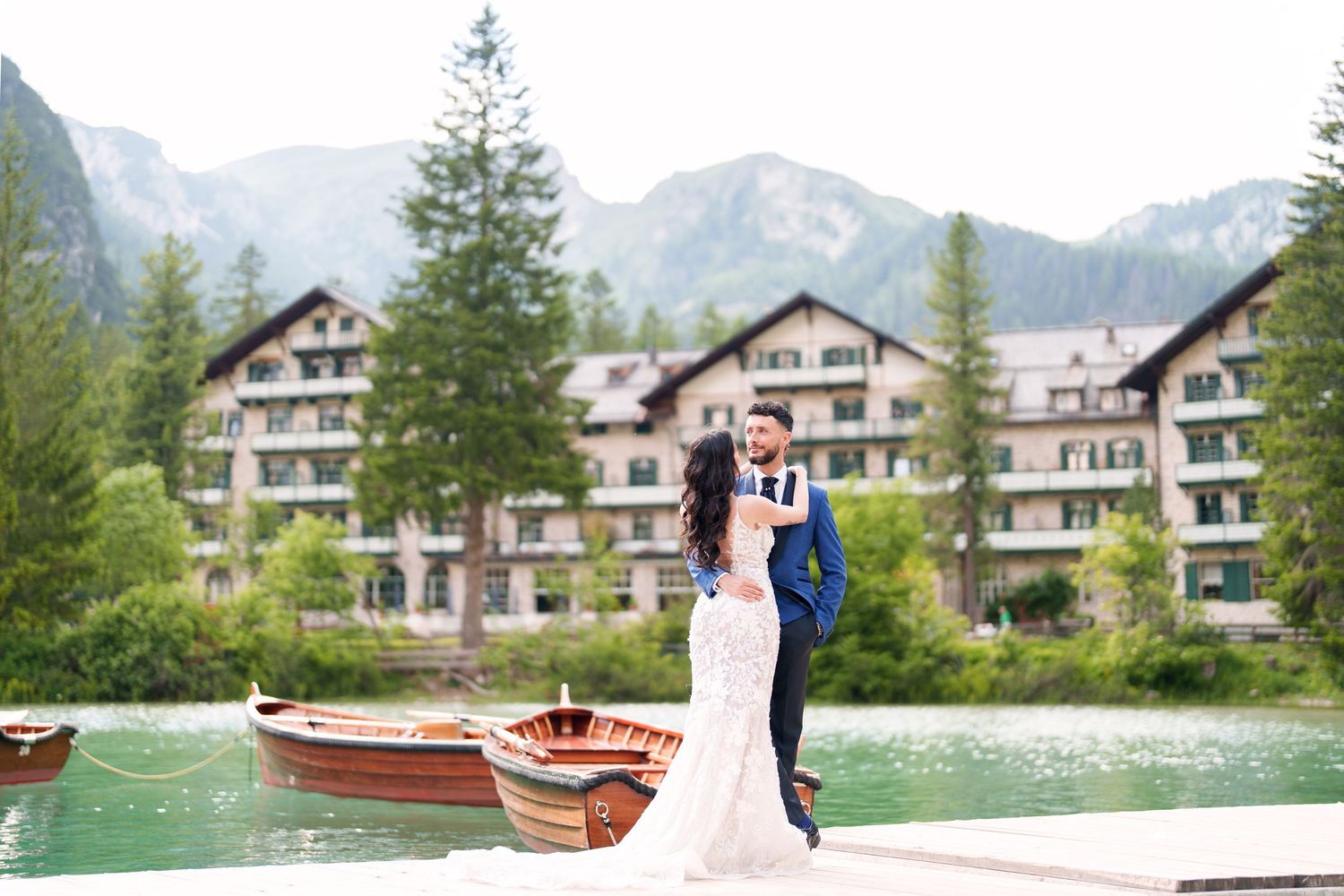 A row of wooden boats and canoes lined up along a dock with mountain lodge accommodations in the background.