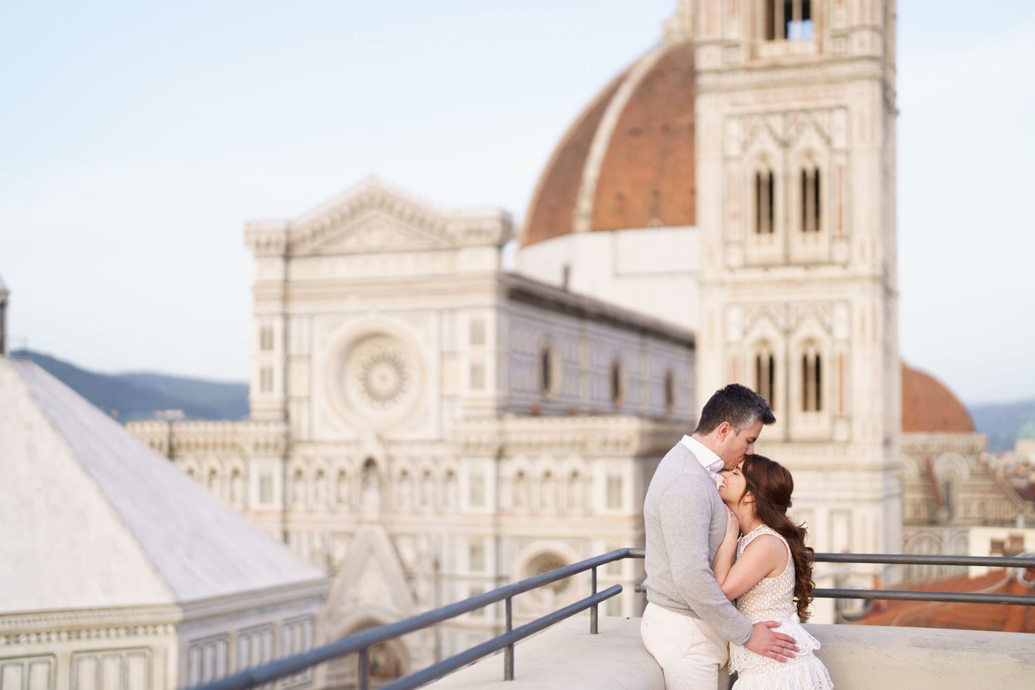 A couple shares a romantic moment in front of the Florence Cathedral's ornate marble facade in Italy.
