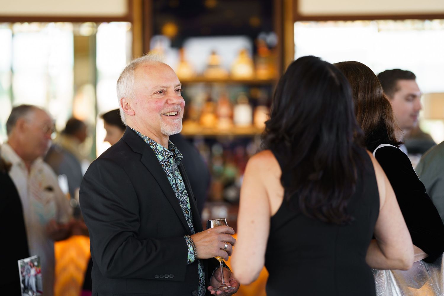 People socializing at an upscale indoor event with bar in background.