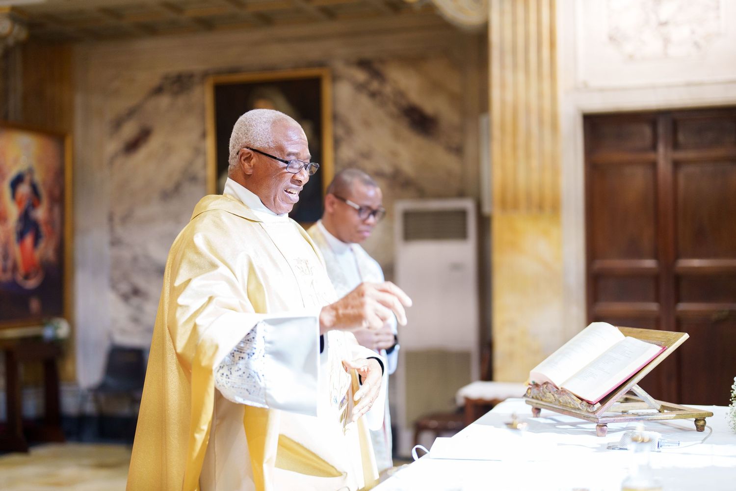 A priest in yellow vestments conducting a religious ceremony at the altar.