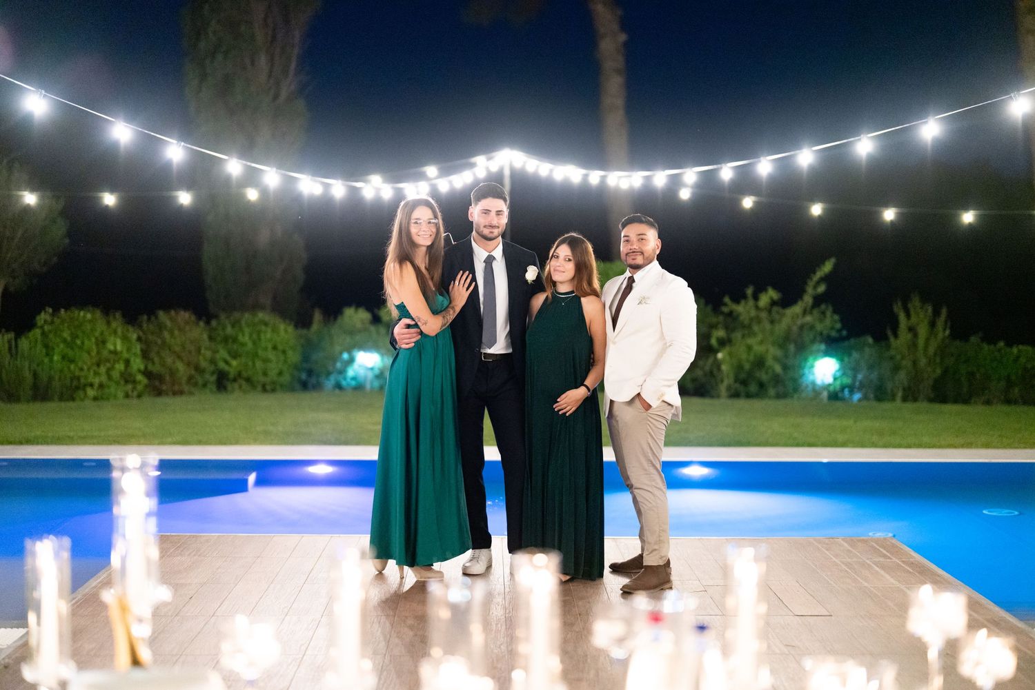 String lights illuminate an evening wedding reception with guests dancing outdoors.