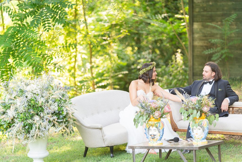 Elegant outdoor wedding reception setup in a lush garden setting with white furniture.