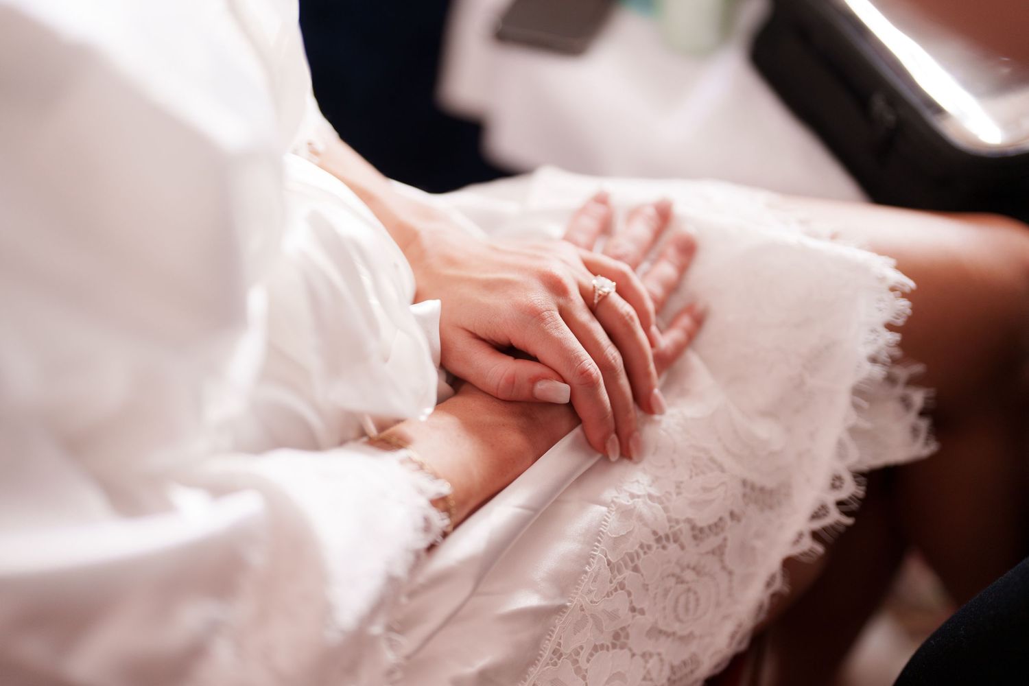 Delicate lace details and hands resting on white fabric.