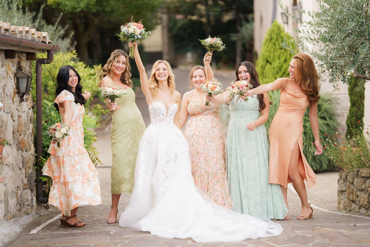 Wedding party in soft pastel colors gathered on Mediterranean-style stone staircase.
