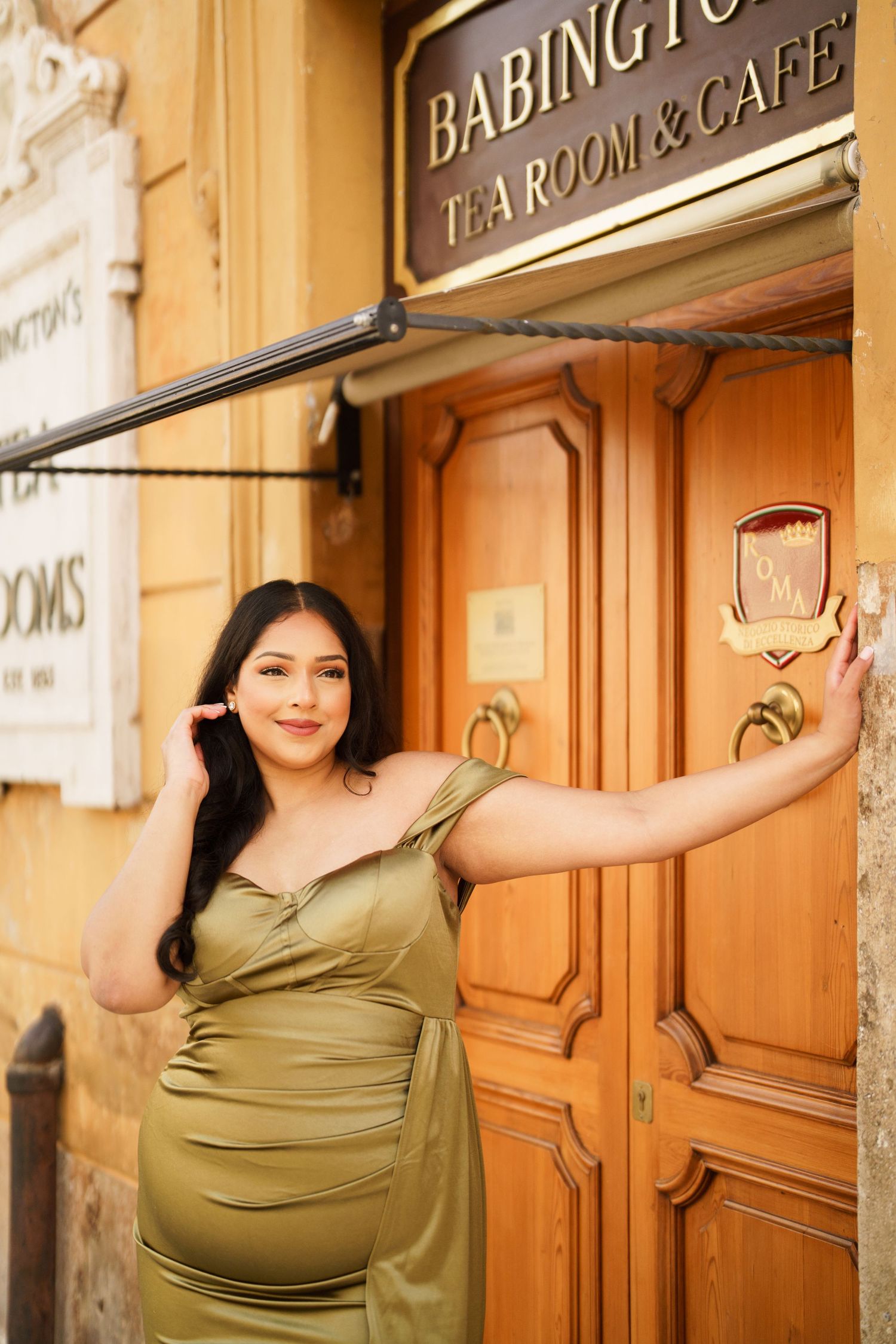 Woman in olive satin dress posing at Babington's Tea Room & Cafe entrance in Rome.