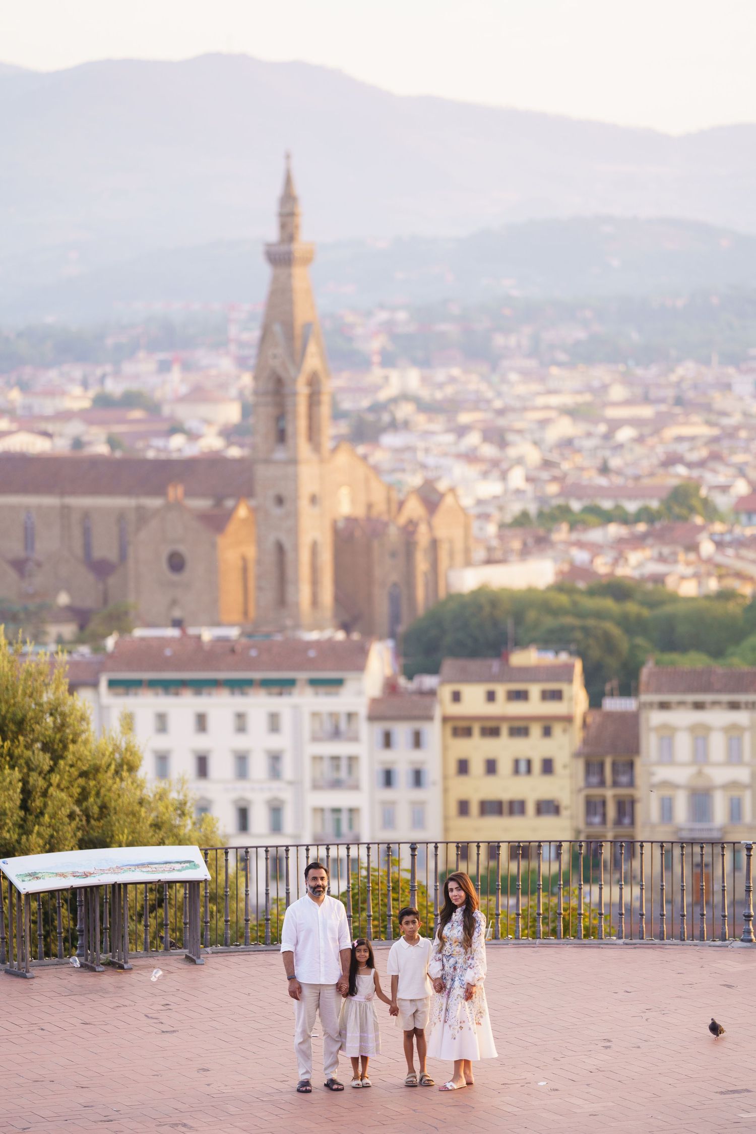 Family of four posing on a terrace overlooking Florence, Italy, with the Basilica di Santa Croce in the background.