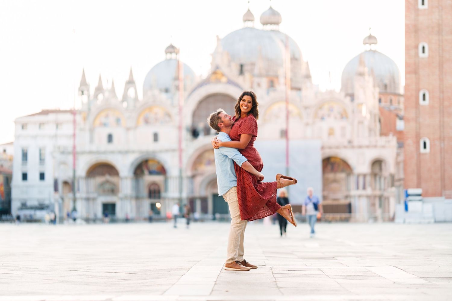 Couple embracing in Piazza San Marco, Venice, with St. Mark's Basilica in the background.