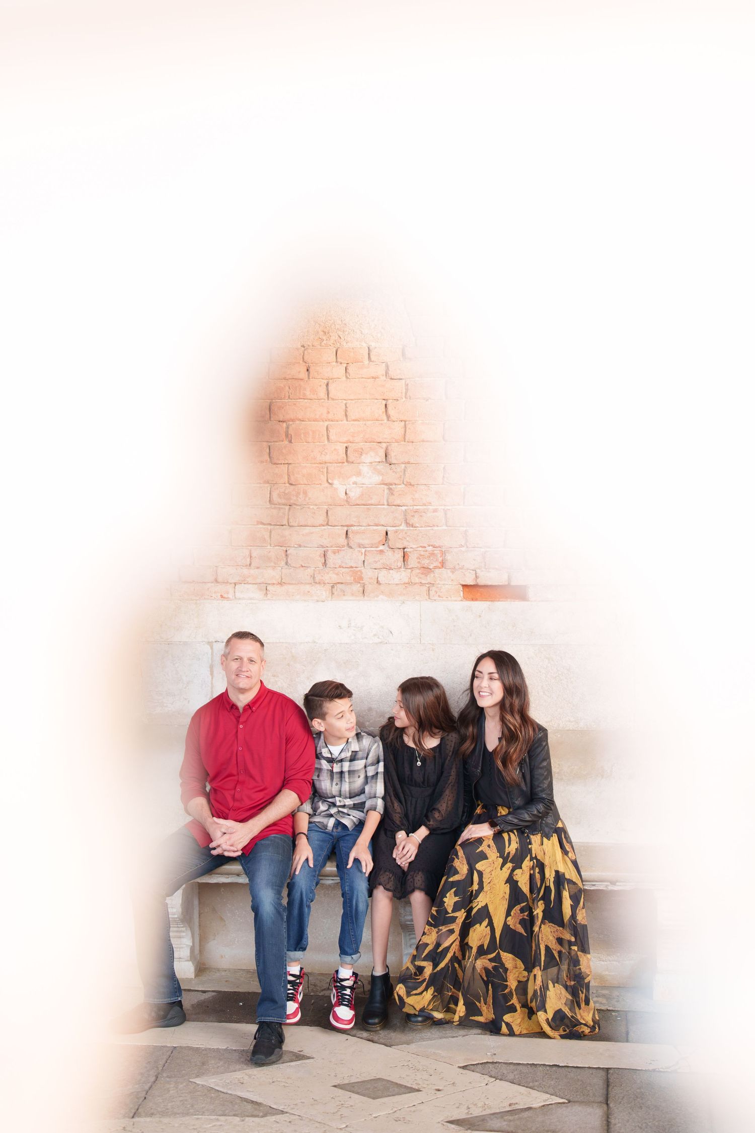 photographer veniceA group of people sitting together on concrete steps with a white brick wall background.