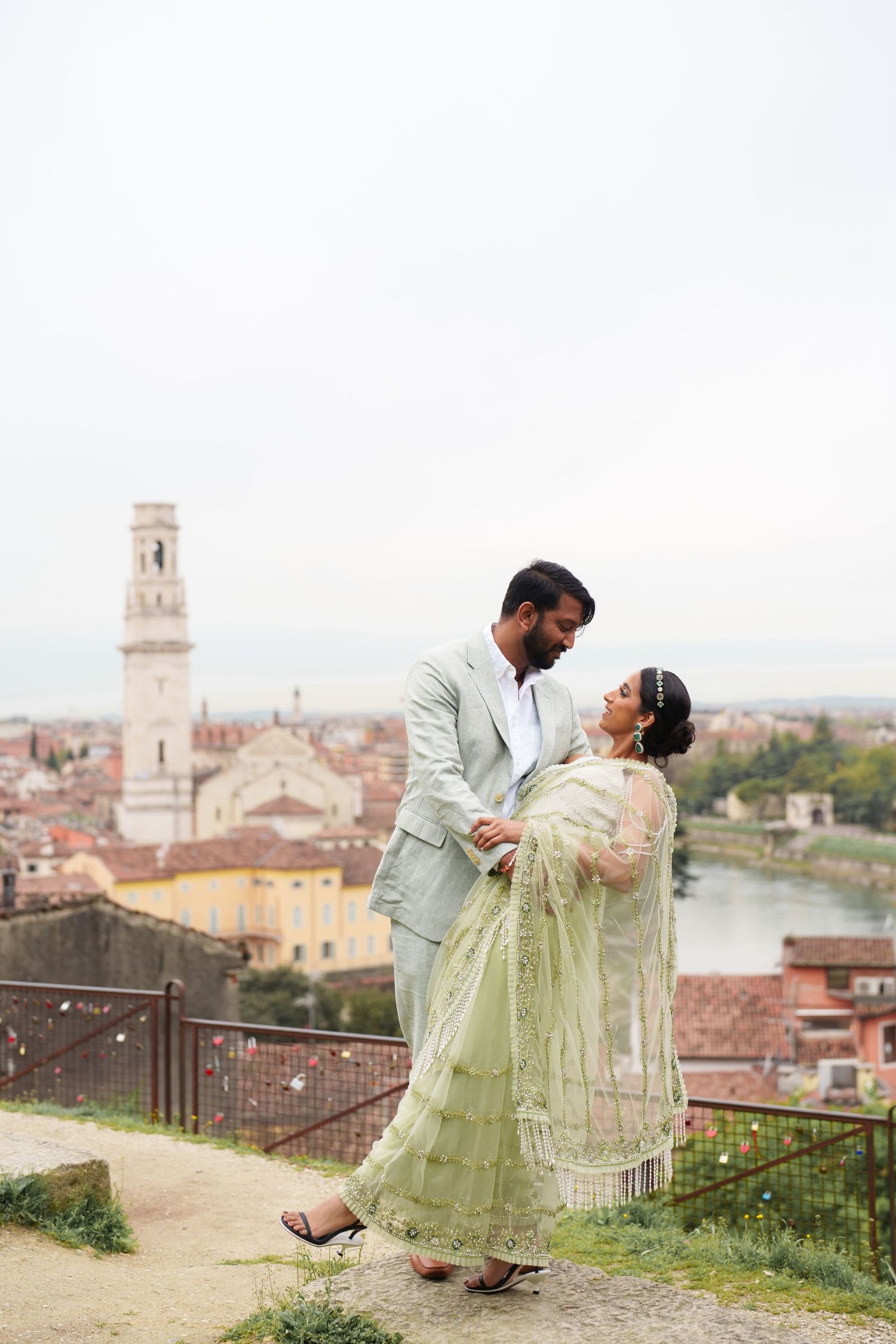A couple in traditional attire share romantic moments against a scenic Italian cityscape backdrop in Lucca, Tuscany.