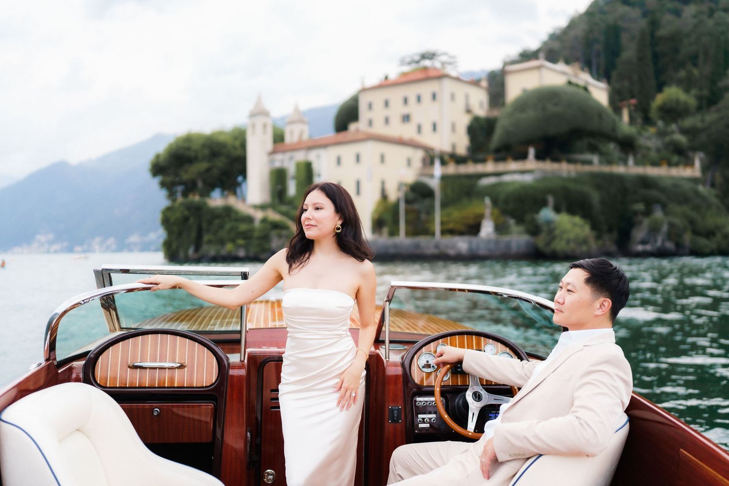 A romantic couple enjoys a scenic boat ride along the Italian coast in a vintage wooden vessel.