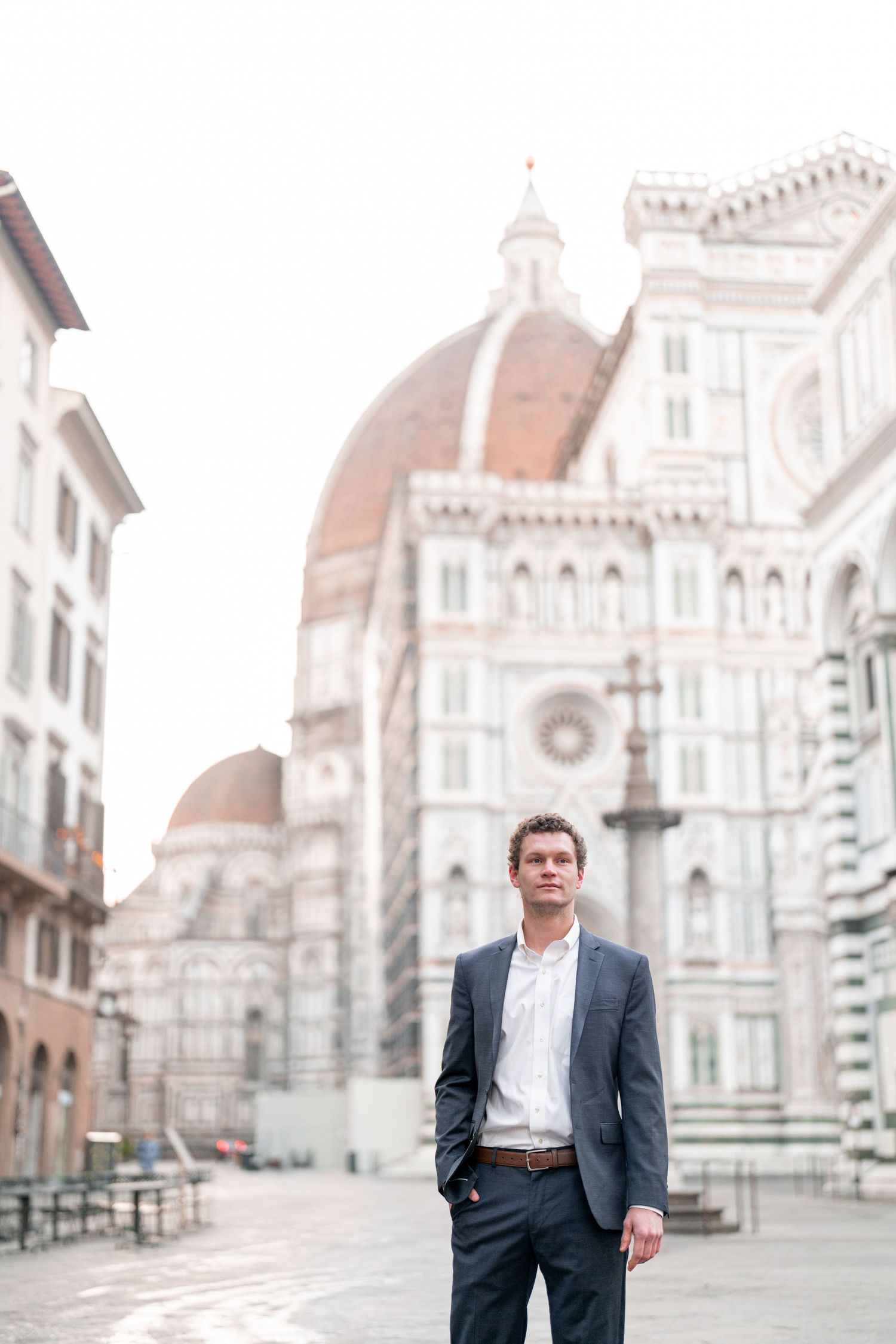 A figure stands in front of the historic Florence Cathedral in Italy wearing a business suit.
