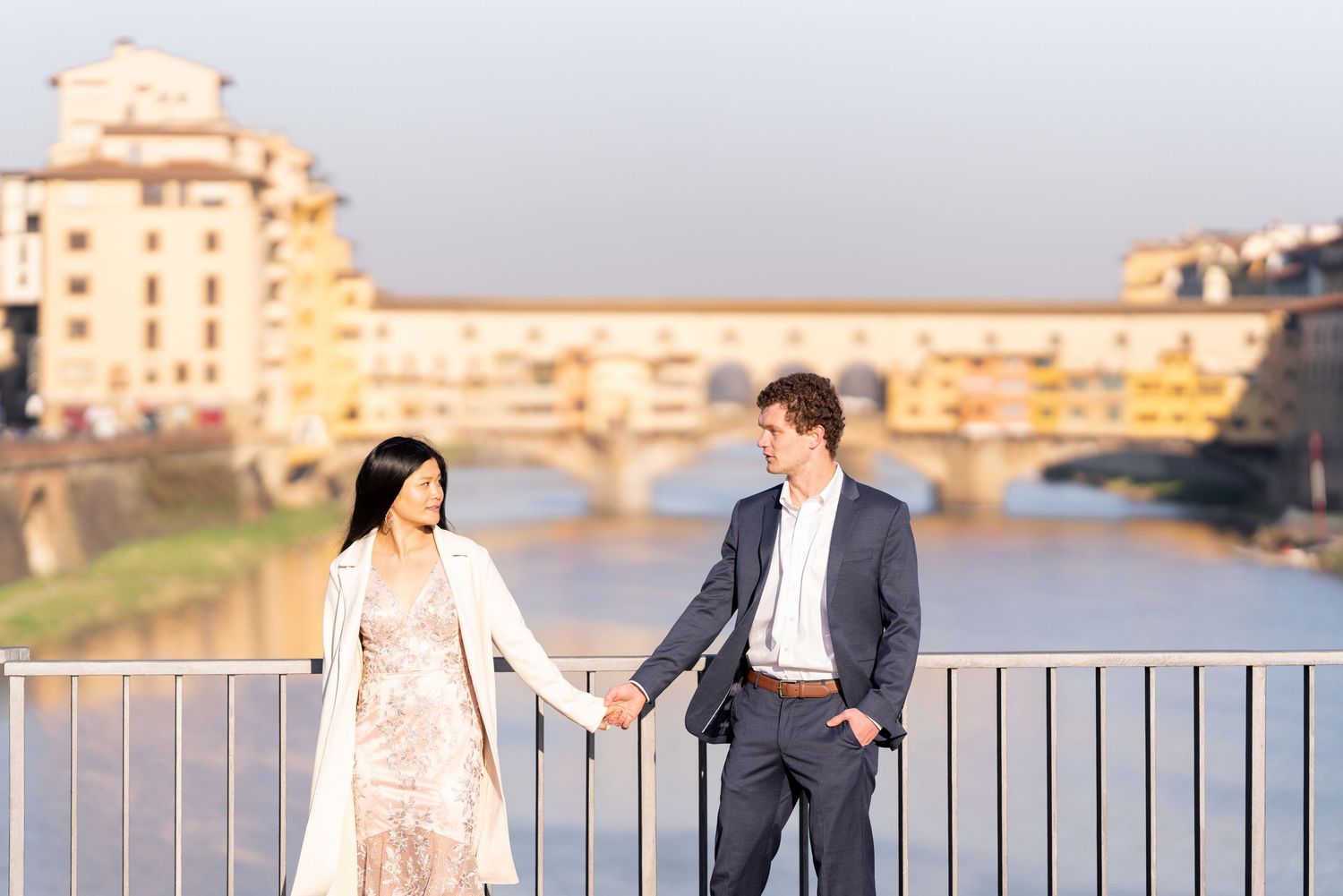 A couple poses together during a sunset engagement photo session along the Ponte Vecchio bridge in Florence, Italy.