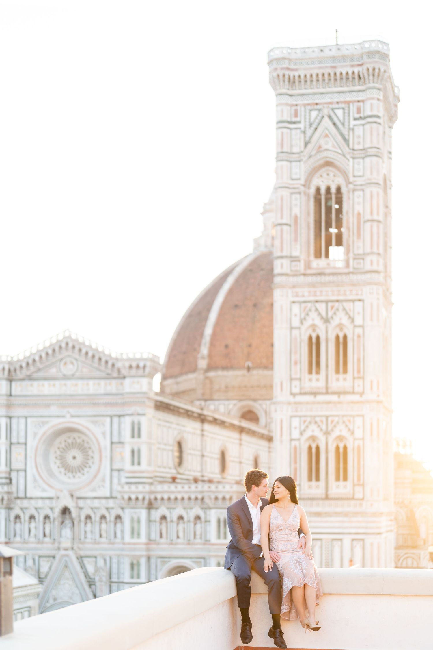 A romantic couple shares a tender moment at sunset in front of the iconic Florence Cathedral in Italy.
