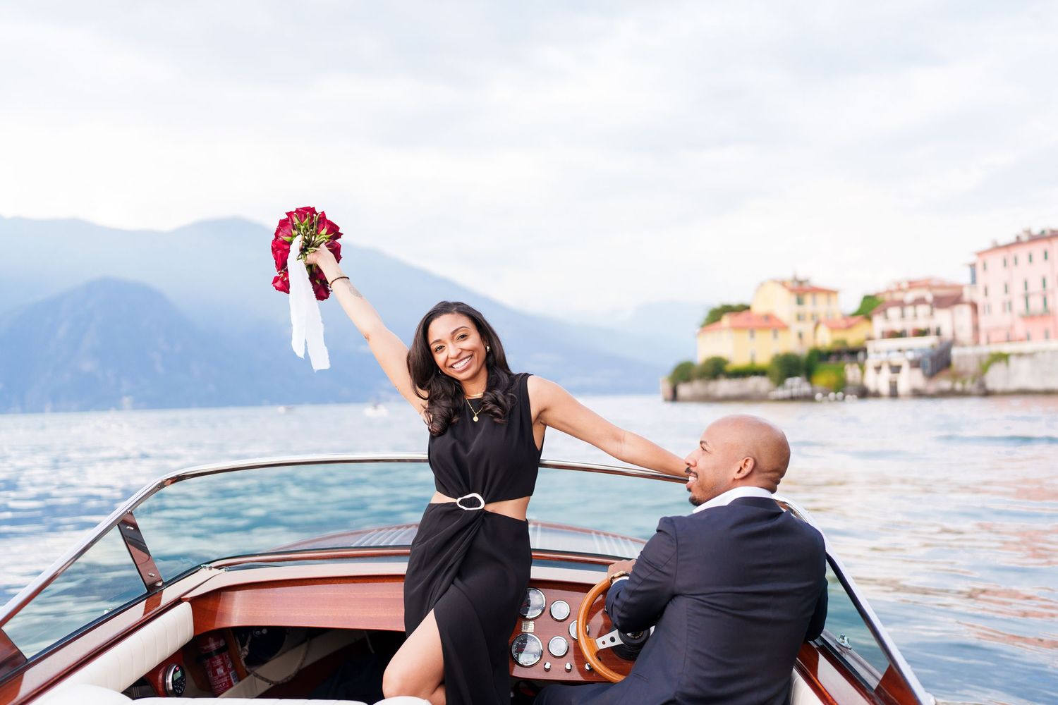 Couple enjoying a romantic boat ride on Lake Como with scenic mountain views and historic Italian villas in background.