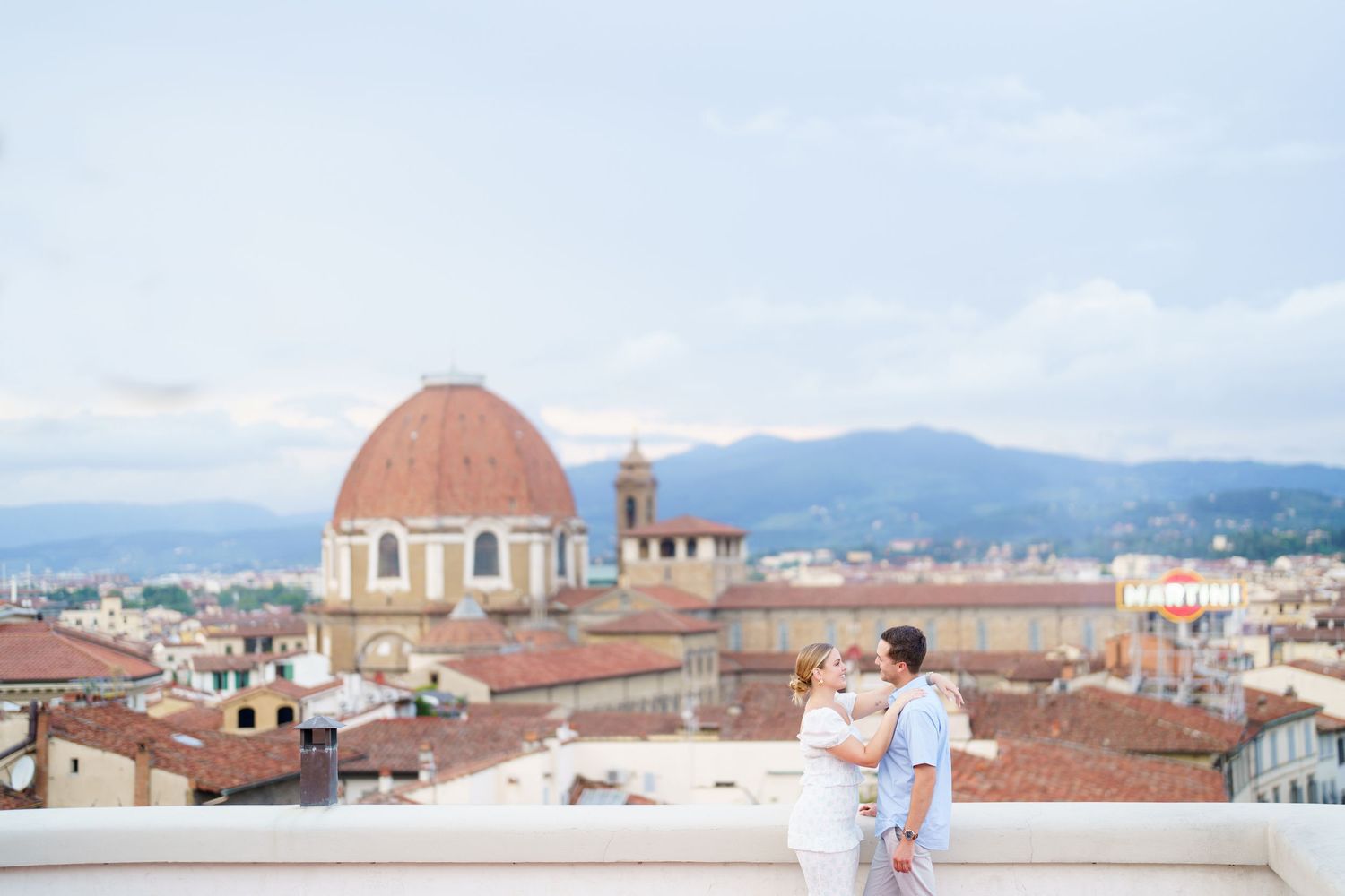 Panoramic views of Florence's historic skyline with terracotta rooftops and mountains in the background during sunset.