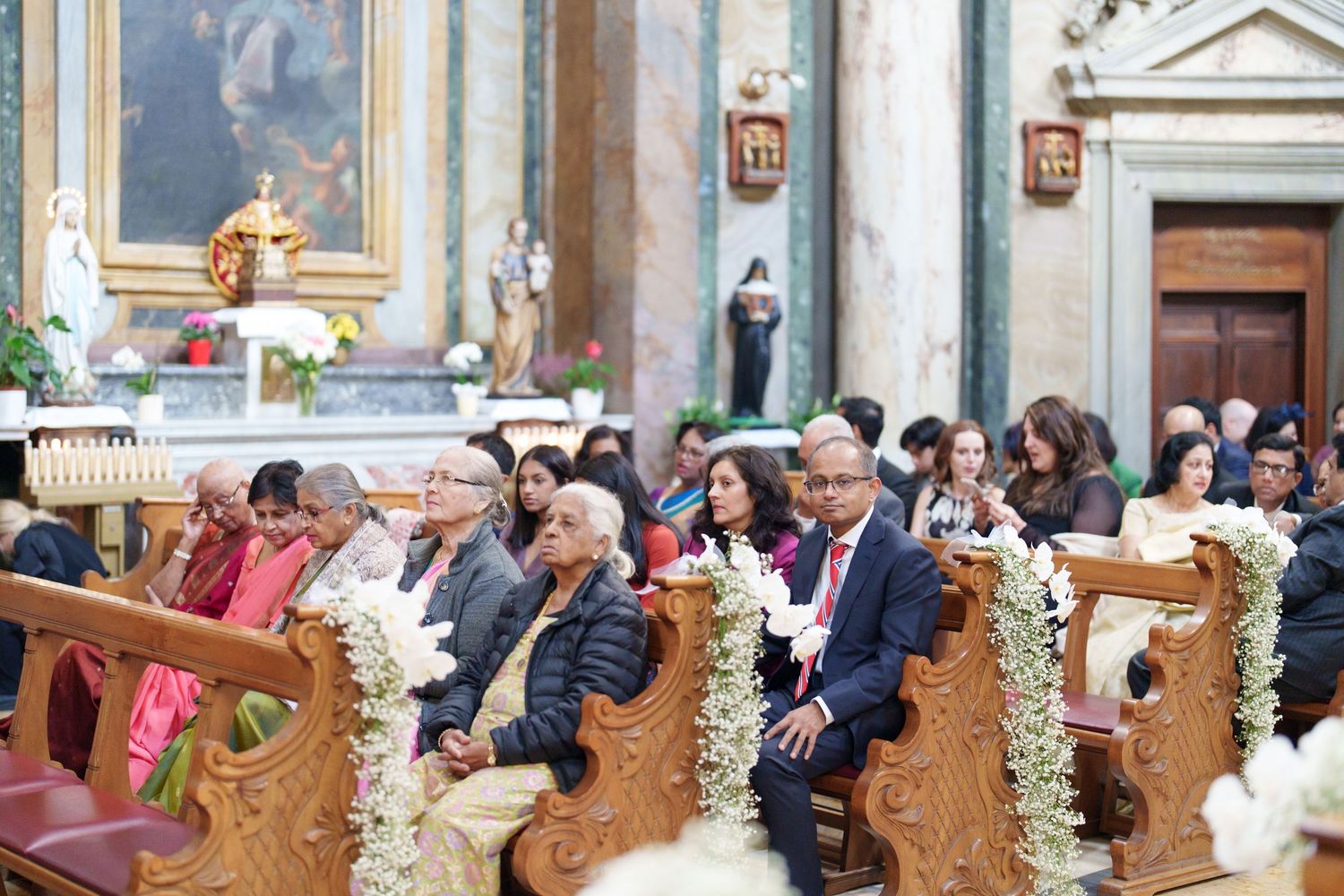 Ornate wooden church pews filled with guests during a formal ceremony.