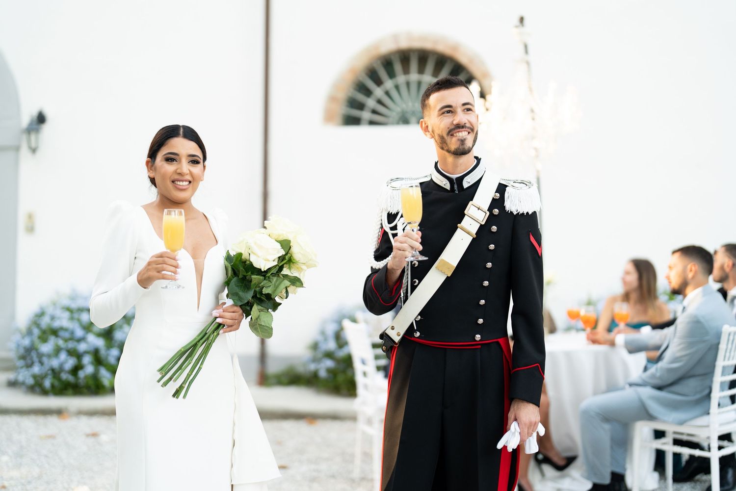 A couple toasts with champagne at their outdoor wedding celebration.