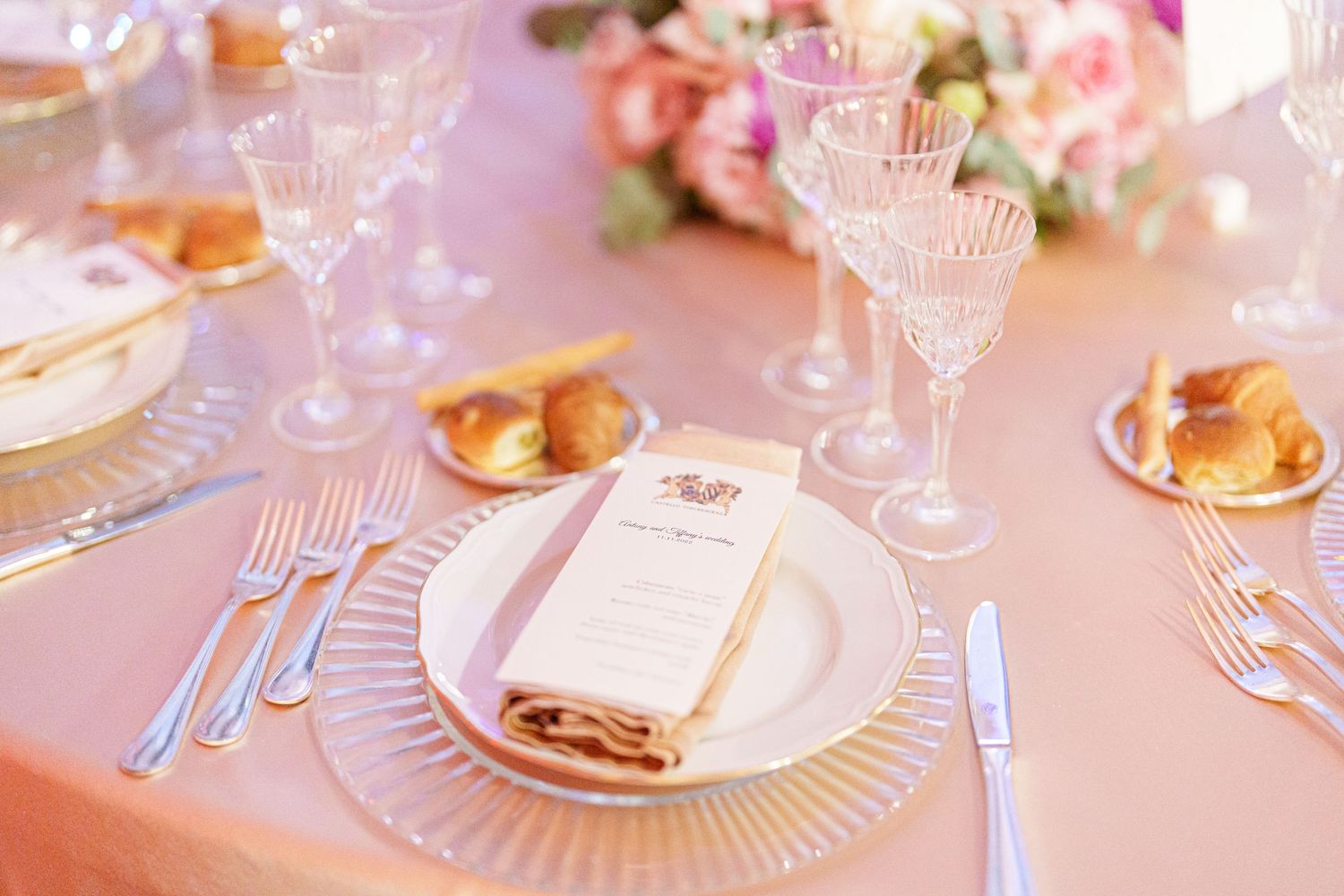 Close-up of formal place settings with crystal glassware and gold accents.