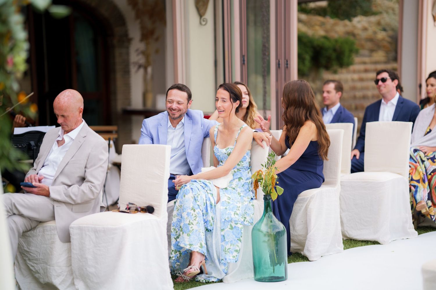 Wedding guests enjoying a celebration at an outdoor venue with white seating arrangements.