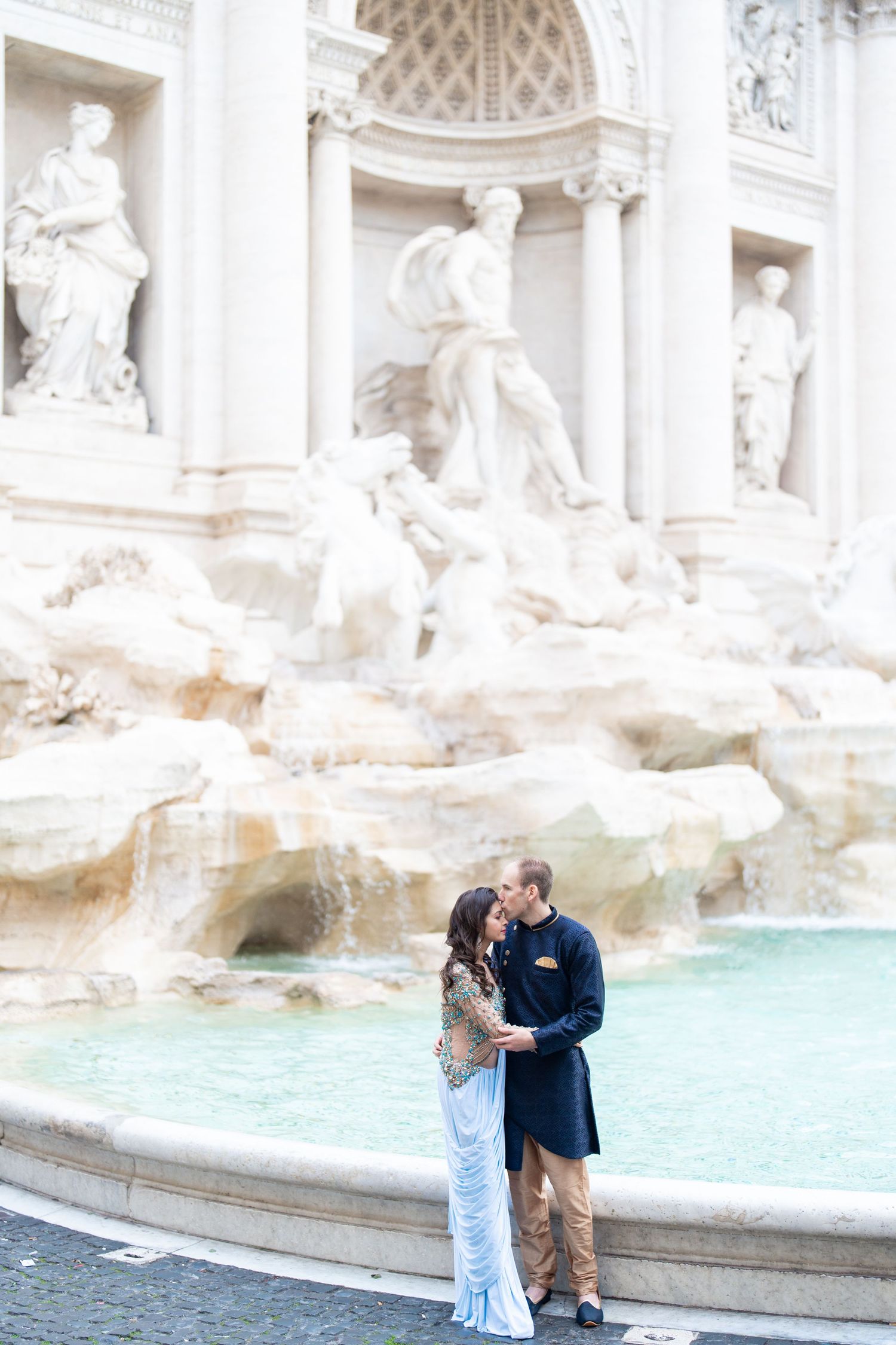 Couple posing for romantic photos in front of the iconic Trevi Fountain in Rome.
