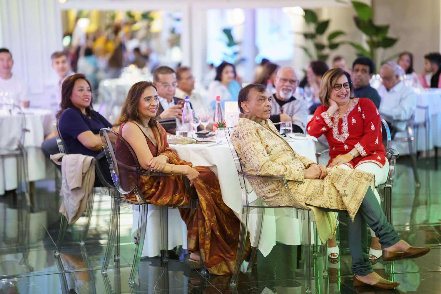 Guests seated at round tables in a bright indoor venue during an event.