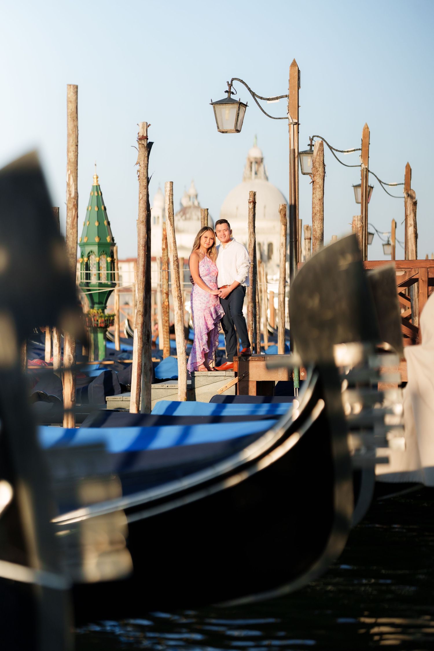 Couple embracing on Venice gondola dock with Santa Maria della Salute basilica in background.