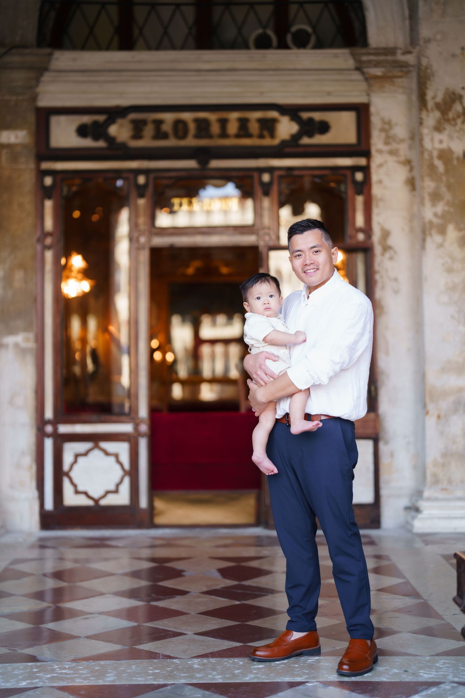 Father holding baby in front of Caffe Florian in Venice, Italy.