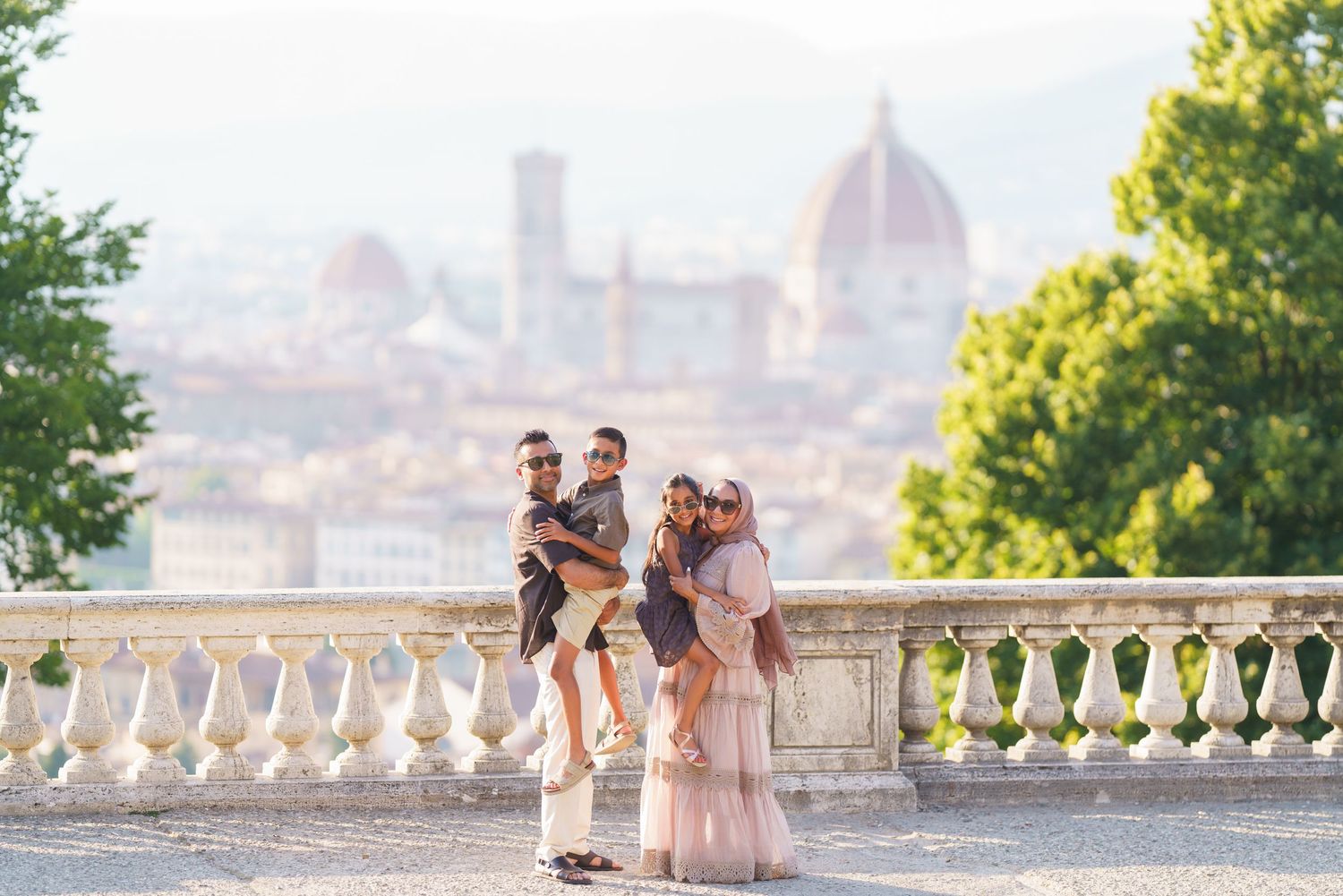 Family posing on a terrace in Florence, Italy, with the iconic Duomo cathedral and cityscape visible in the background.