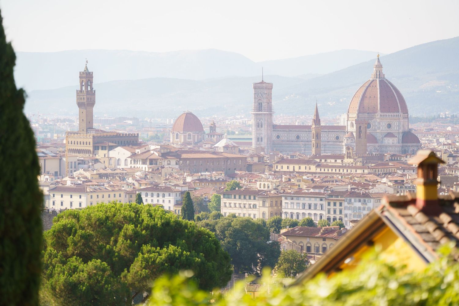Panoramic view of Florence, Italy skyline featuring the iconic Duomo cathedral and Palazzo Vecchio tower.