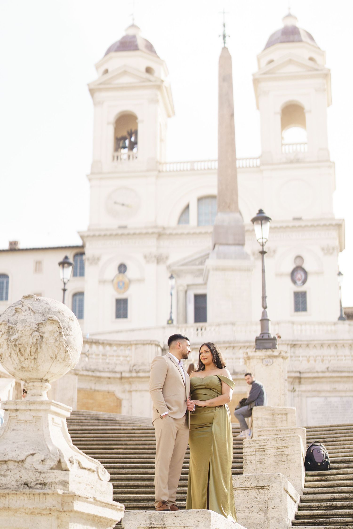 Couple posing on the Spanish Steps in Rome, Italy, with the Trinità dei Monti church in the background.