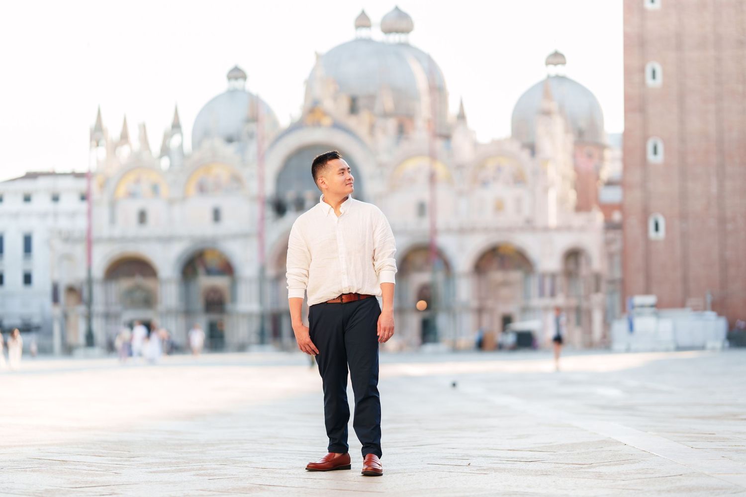 Man standing in St. Mark's Square Venice with Basilica di San Marco in background on sunny day.
