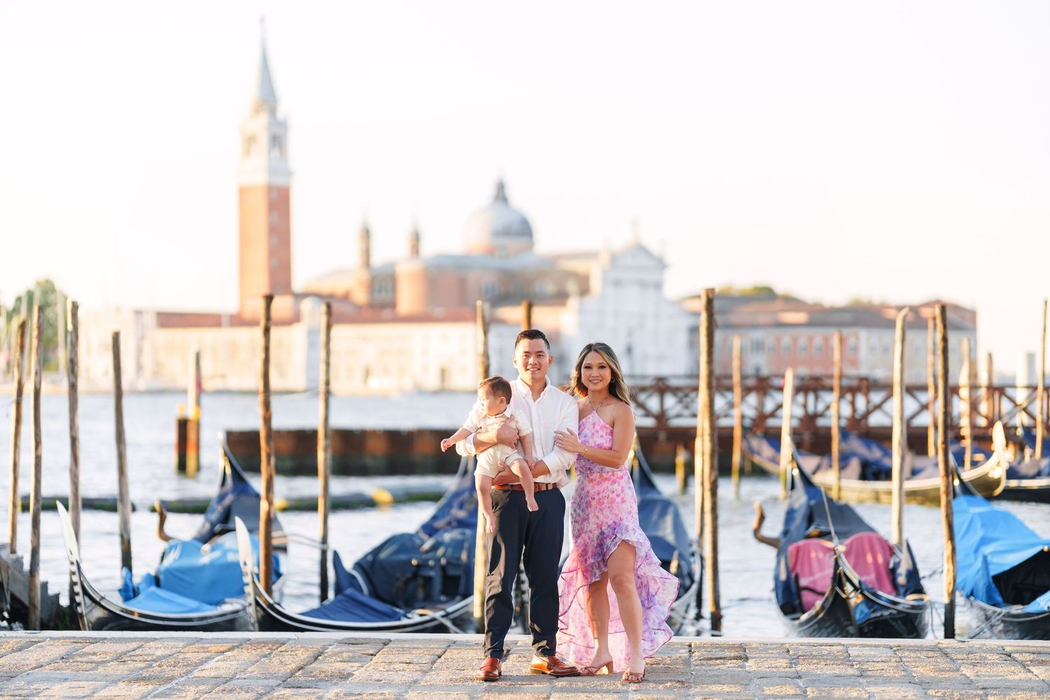Family posing with gondolas and San Giorgio Maggiore church in Venice, Italy at golden hour.