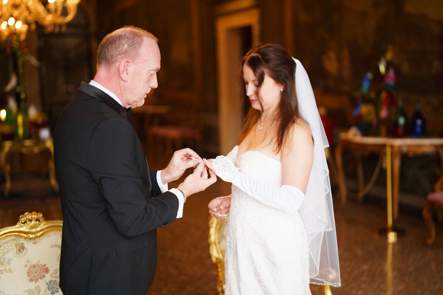 A couple shares a romantic dance during their wedding reception in a warmly lit ballroom.