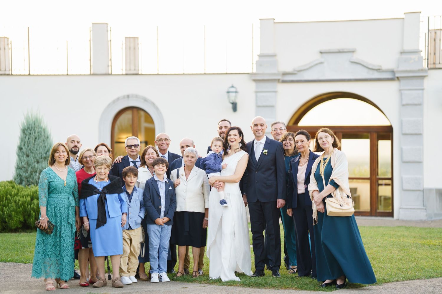 Wedding party and family members posed together outside church entrance.