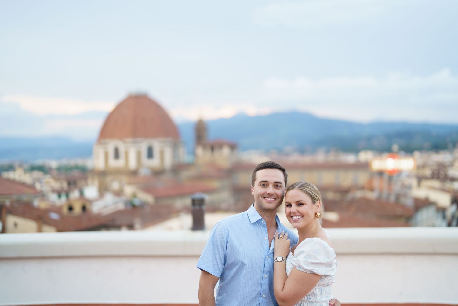 A couple embraces while enjoying the scenic view of Florence's historic skyline and architecture during sunset.