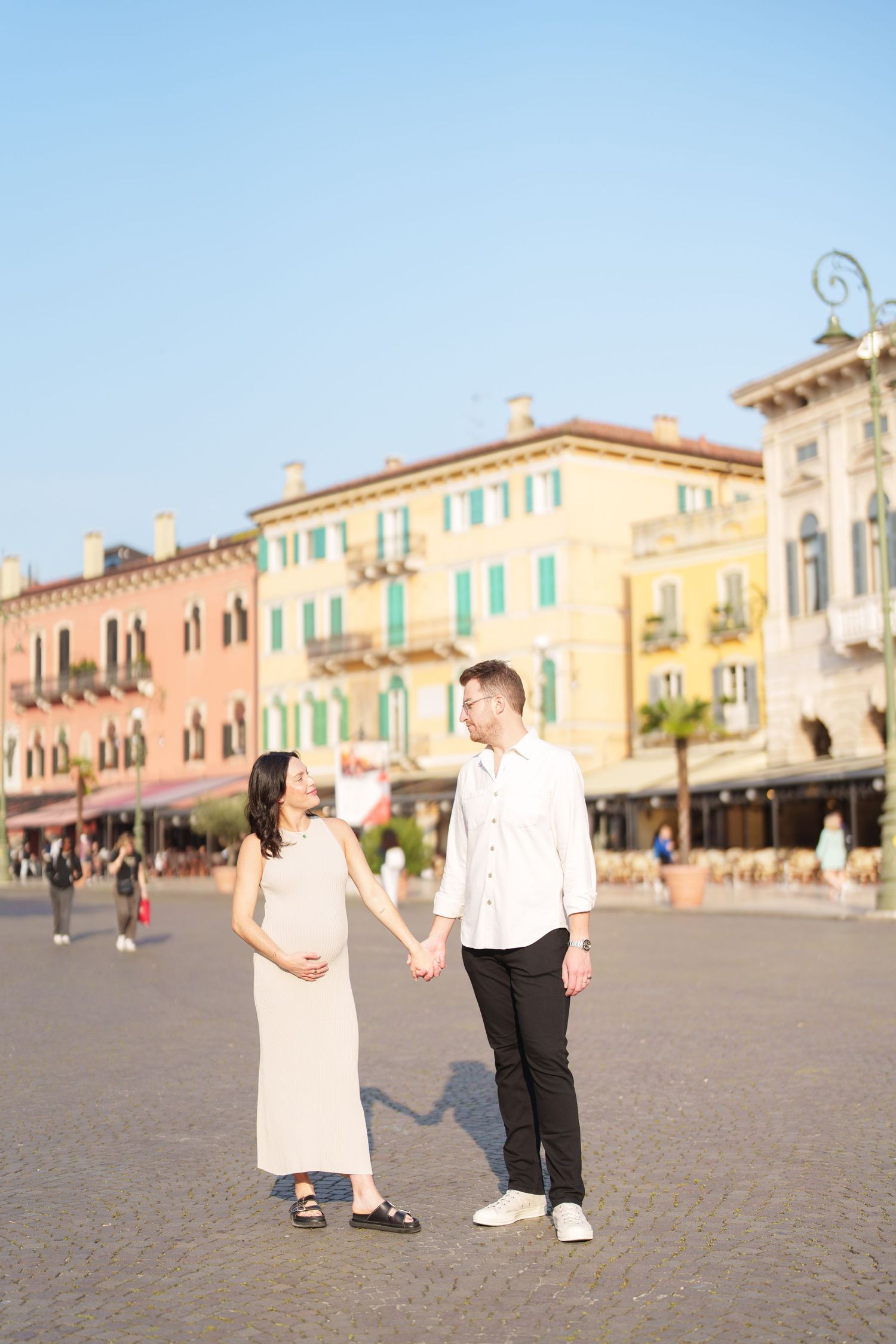 A couple shares a romantic moment in a picturesque Italian plaza with historic buildings in the background.