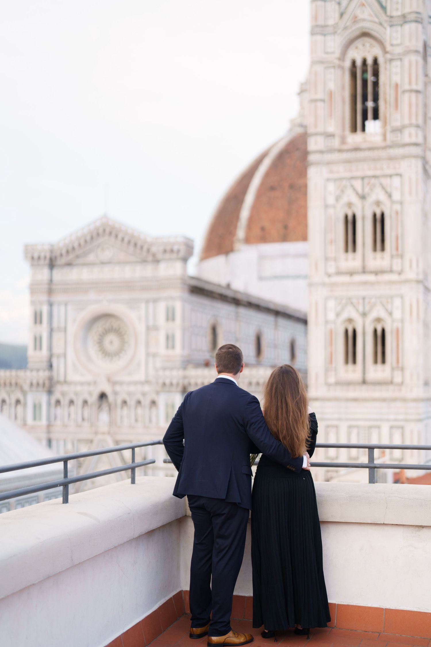 A couple admires Florence Cathedral's iconic dome from a rooftop terrace in Italy.
